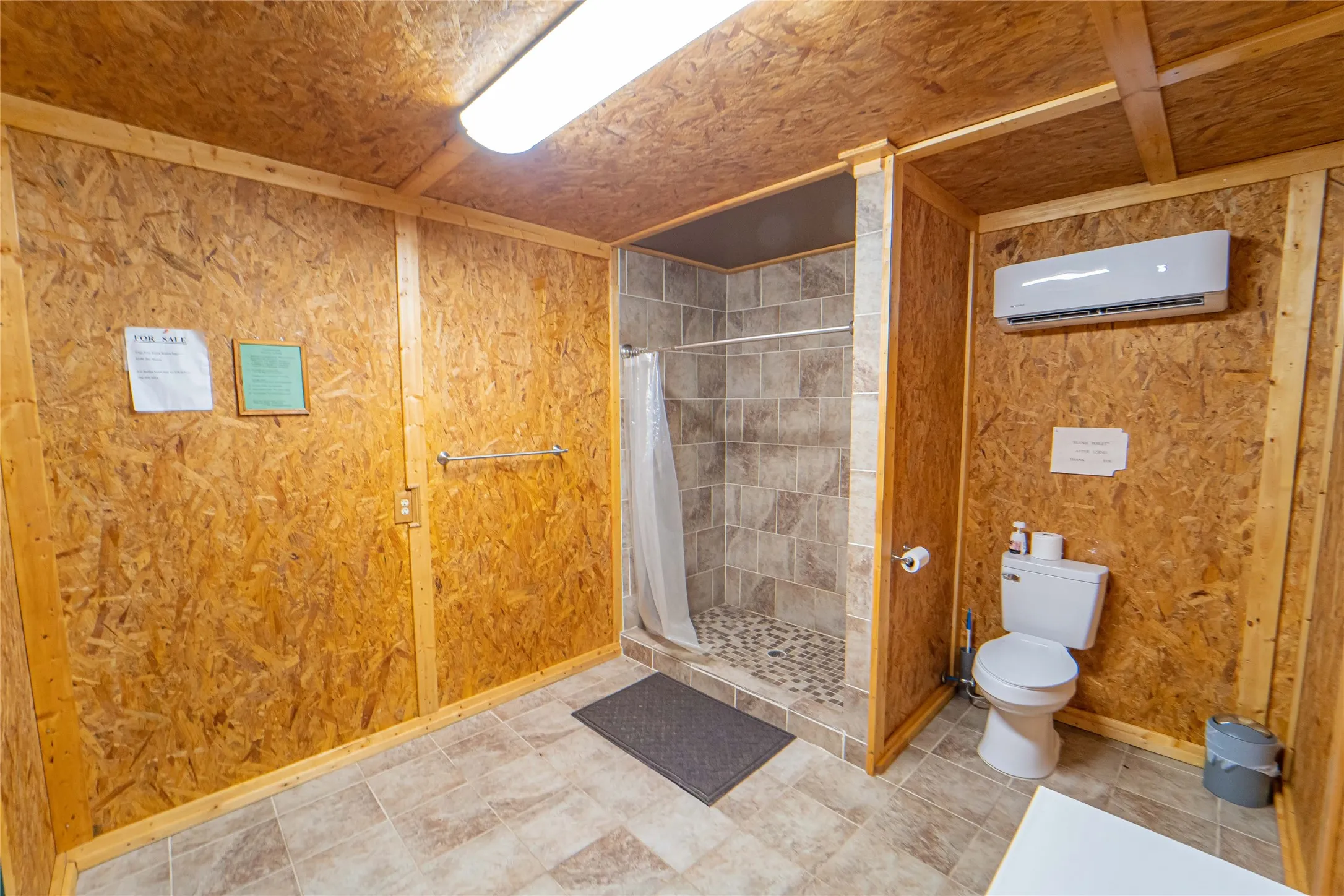 Bathroom featuring a shower stall, wood walls, and a wall mounted air conditioner