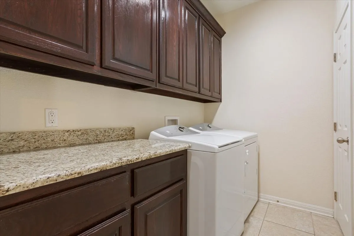 Laundry room with cabinet space, light tile patterned floors, and washing machine and dryer