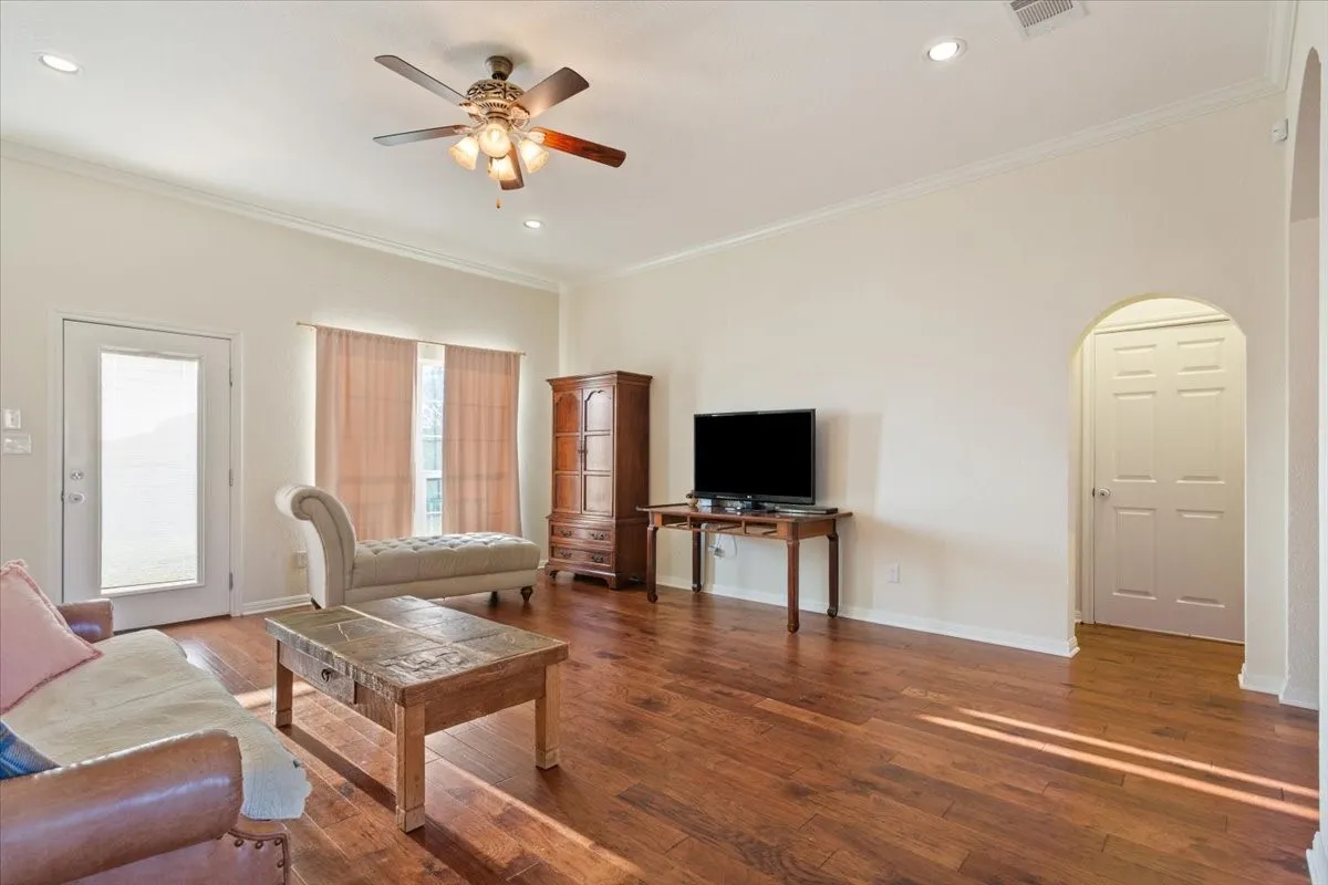 Living area with crown molding, a ceiling fan, hardwood / wood-style flooring, recessed lighting, and arched walkways