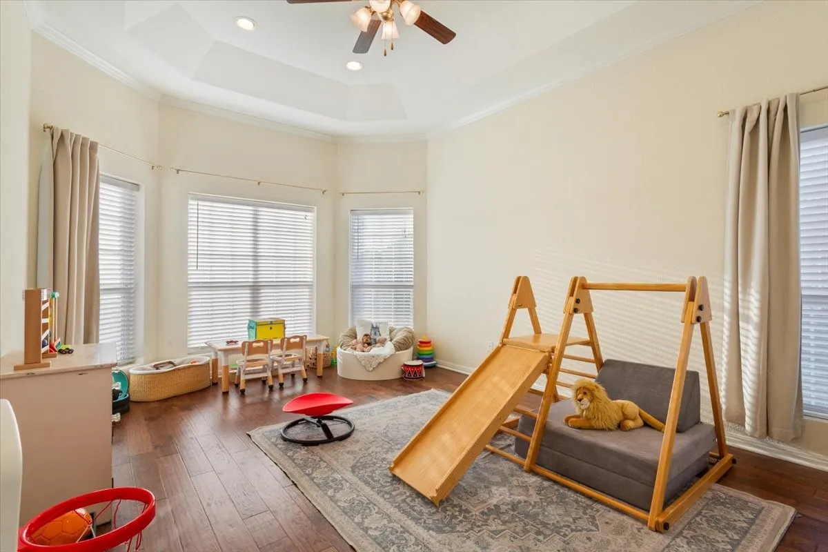 Rec room with healthy amount of natural light, dark wood finished floors, and crown molding