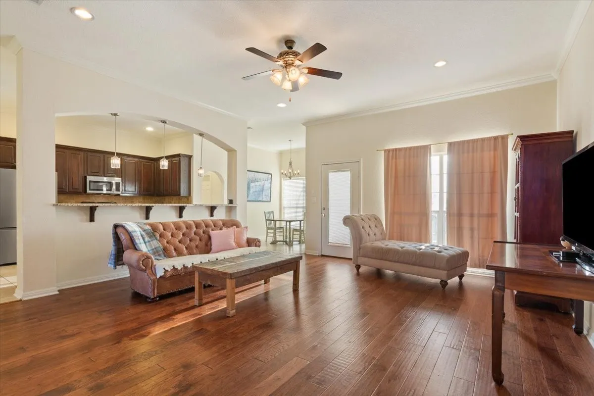 Living area with ornamental molding, dark wood-style flooring, ceiling fan, a chandelier, and recessed lighting