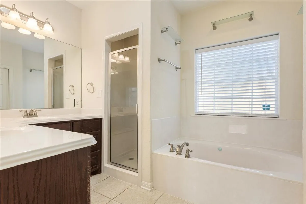 Bathroom featuring vanity, light tile patterned floors, a shower stall, and a garden tub
