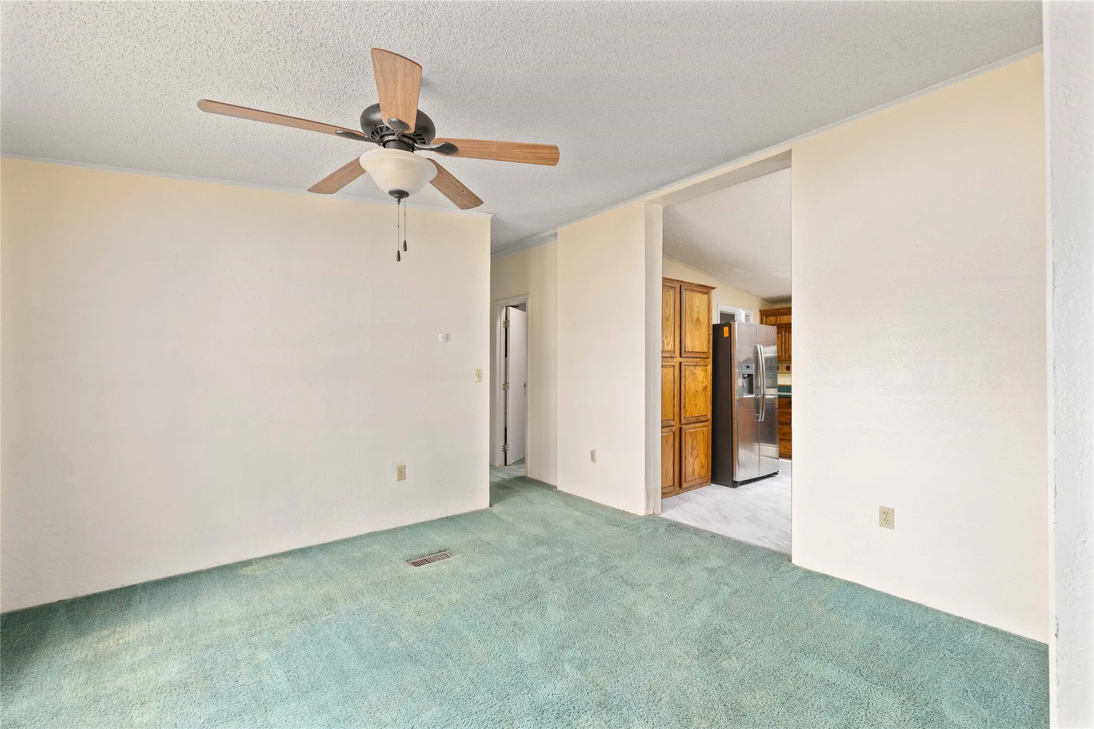 Spare room featuring a ceiling fan, a textured ceiling, light carpet, and lofted ceiling