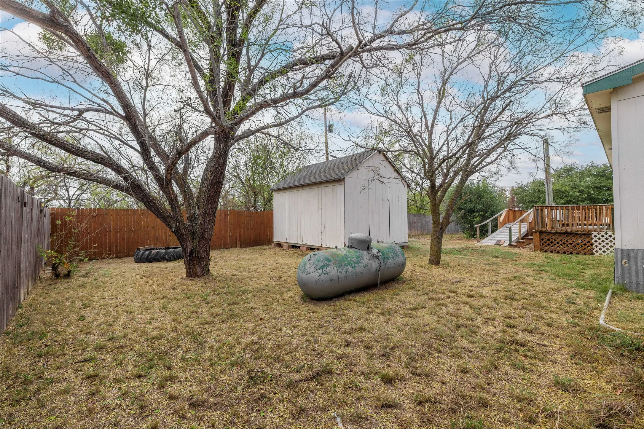 Fenced backyard with a storage shed and a wooden deck