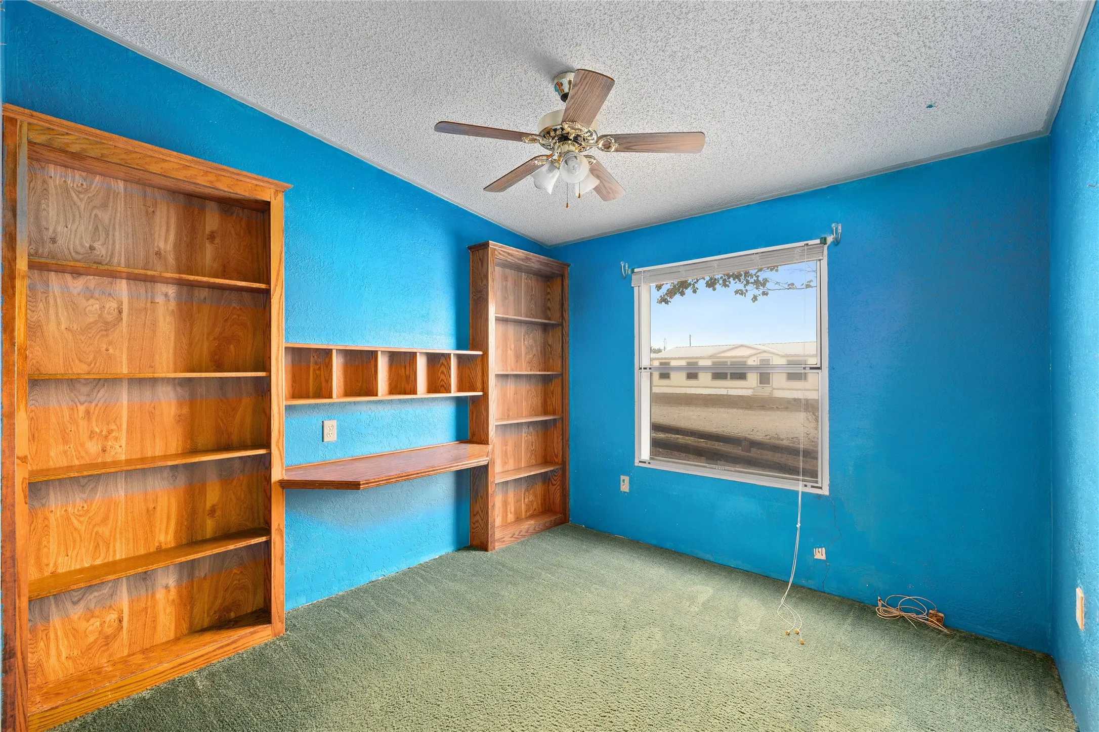 Unfurnished bedroom with ceiling fan, a textured ceiling, carpet flooring, and a textured wall