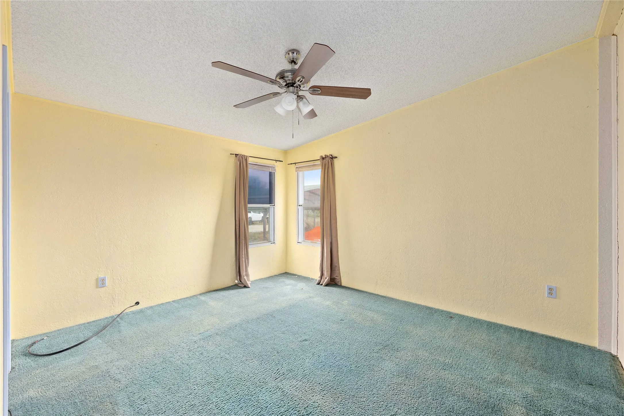 Empty room featuring carpet floors, a textured ceiling, a textured wall, and ceiling fan