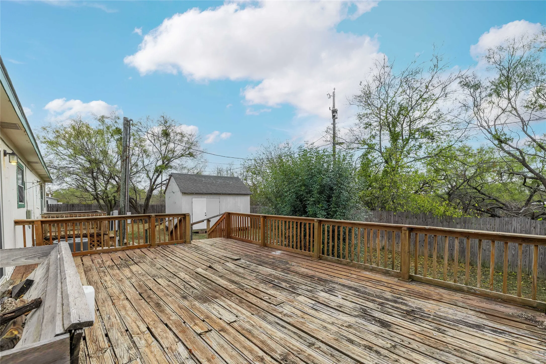 Wooden deck with a fenced backyard and a storage unit