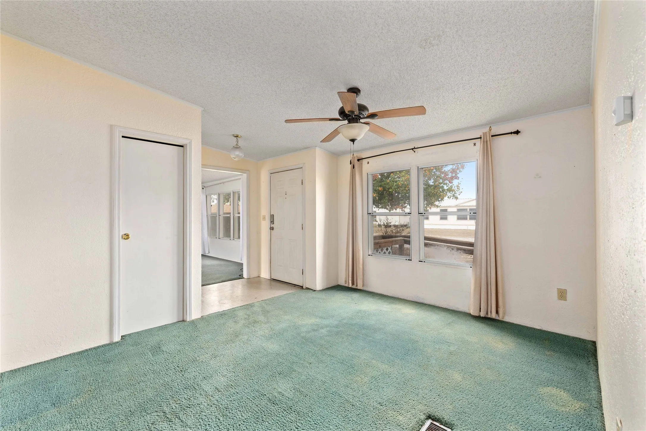 Carpeted empty room with ceiling fan and a textured ceiling