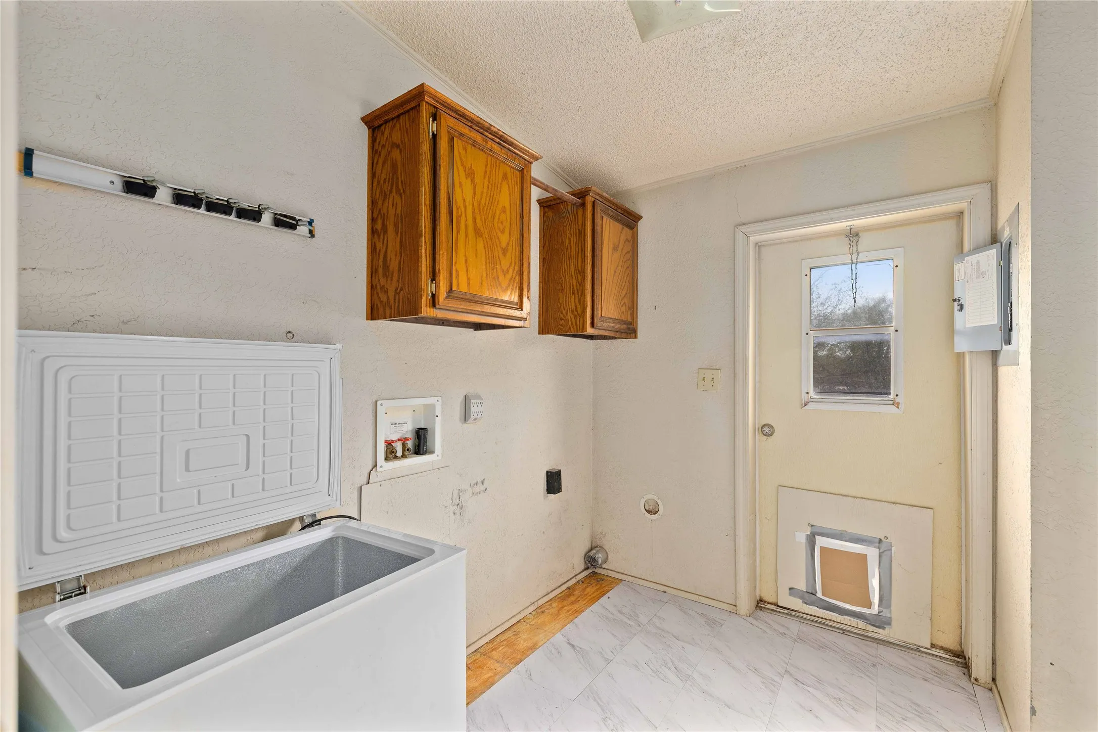 Washroom featuring cabinet space, hookup for a washing machine, a textured ceiling, and light marble finish floors