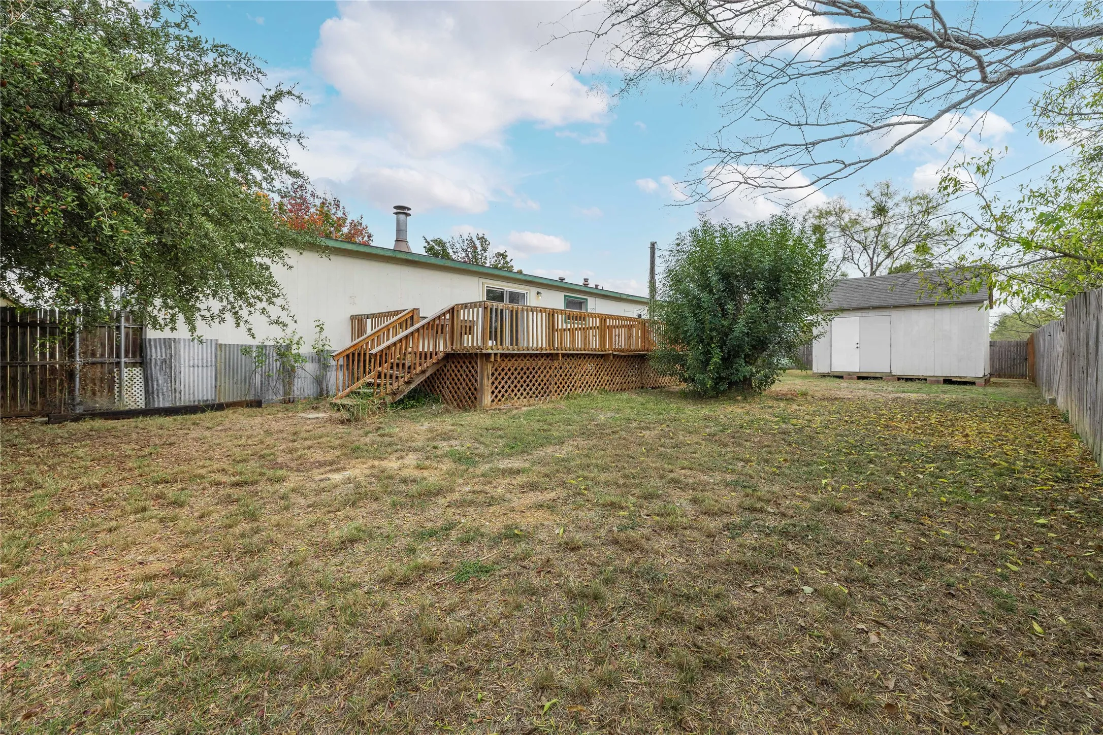 Fenced backyard featuring a storage shed, a wooden deck, and stairway