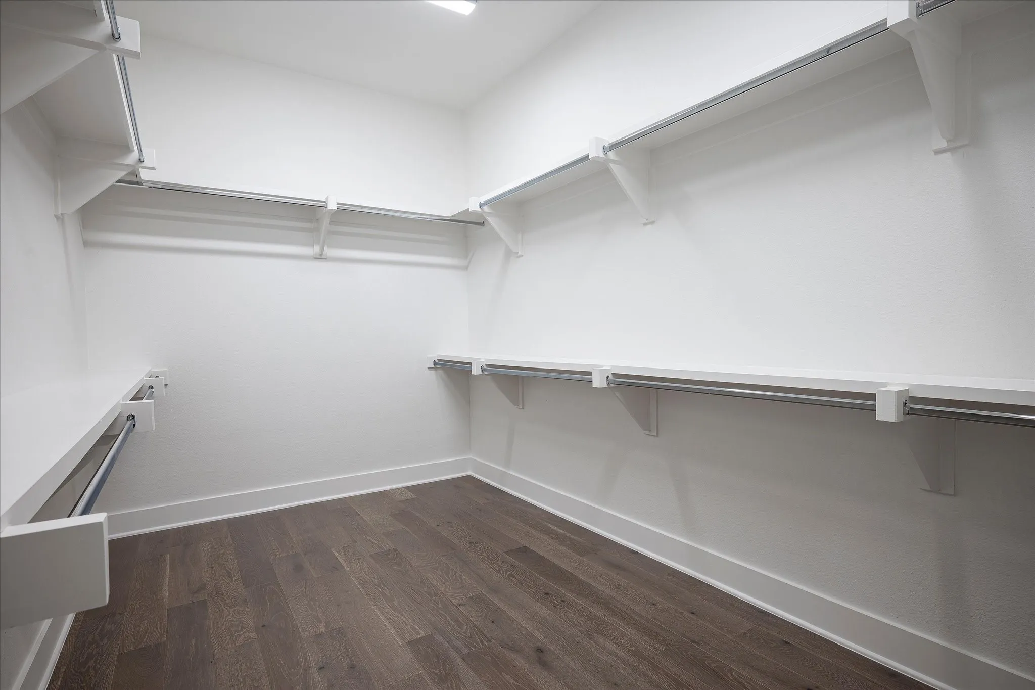 Walk in closet with dark wood-type flooring