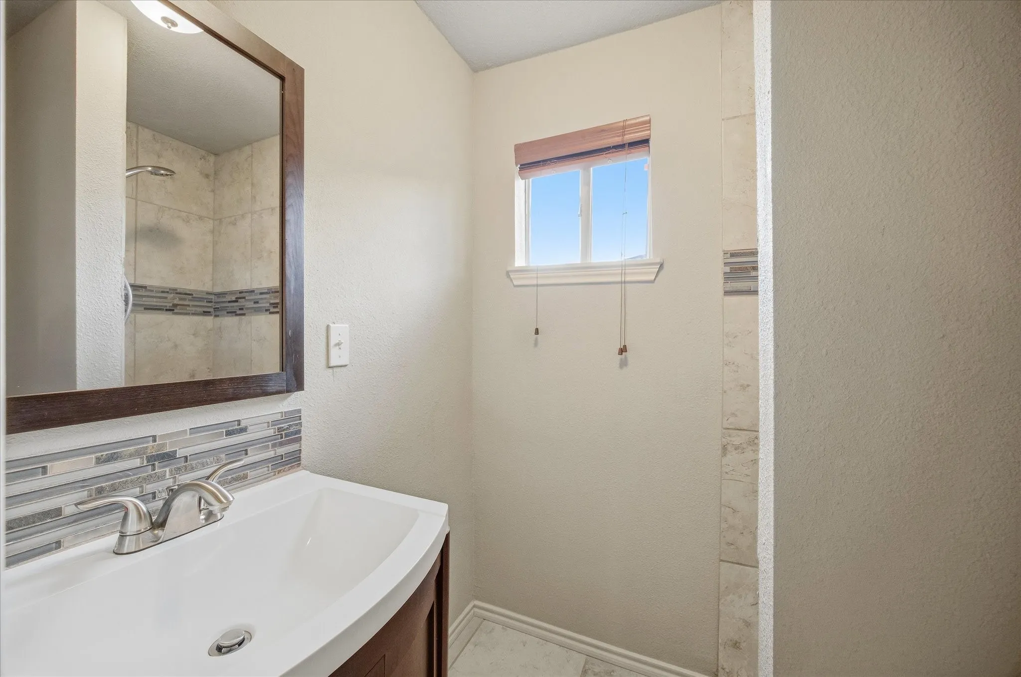 2nd Bathroom with vanity a textured wall and backsplash