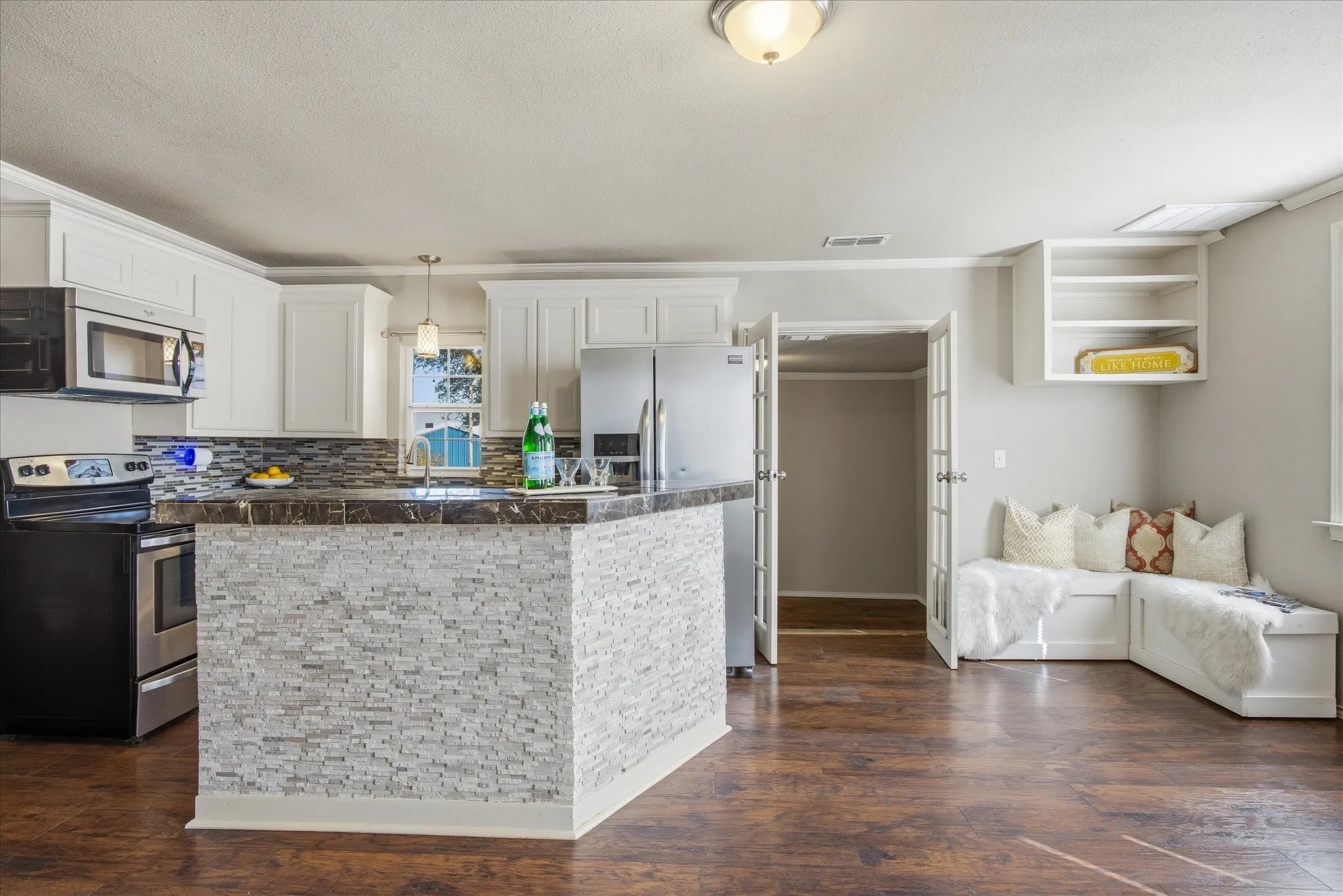Kitchen with tile counters, stainless steel appliances, white cabinetry, dark wood-style flooring and crown molding