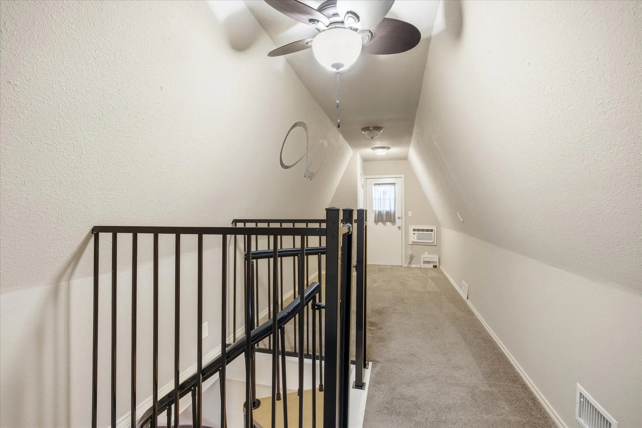 Corridor with light colored carpet, an upstairs landing and lofted ceiling