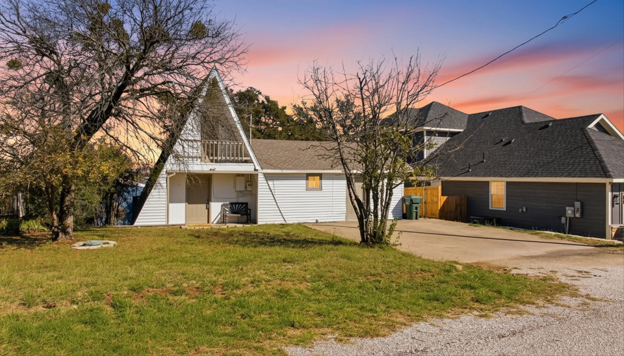 A-frame style home with a lawn, a shingled roof, concrete driveway and a balcony