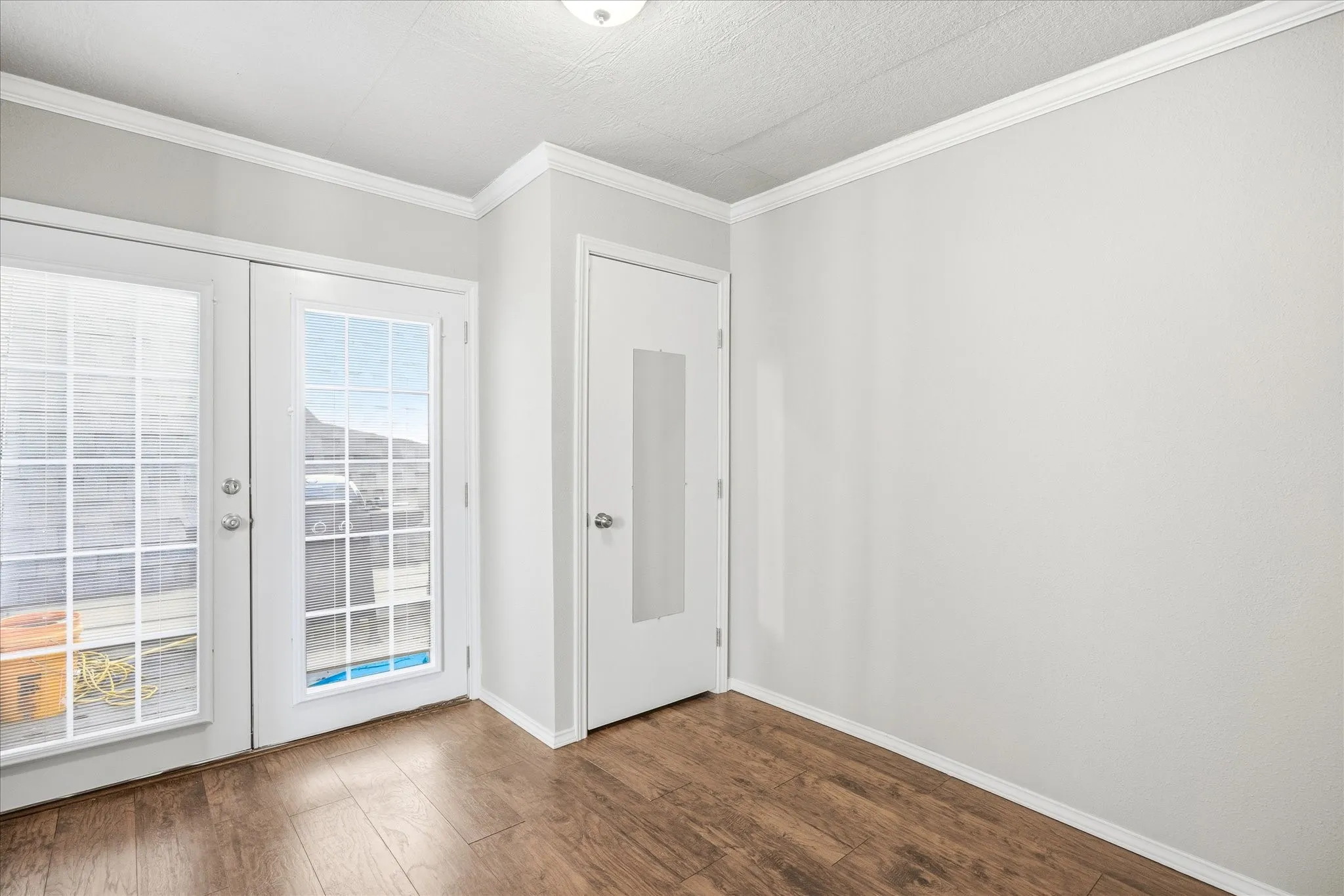 Spare room with french doors, dark wood-style flooring and crown molding