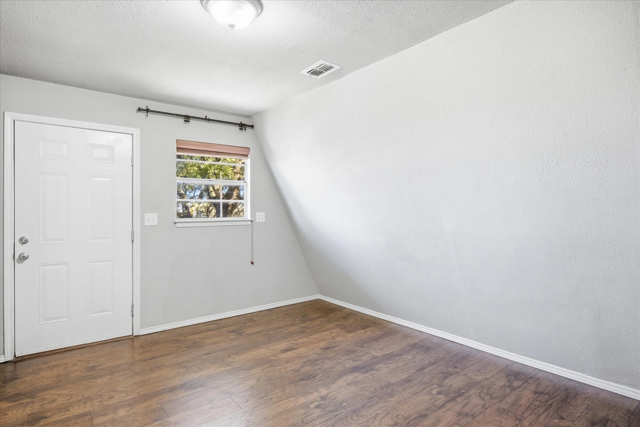 Primary bedroom featuring dark wood-style flooring and a textured ceiling