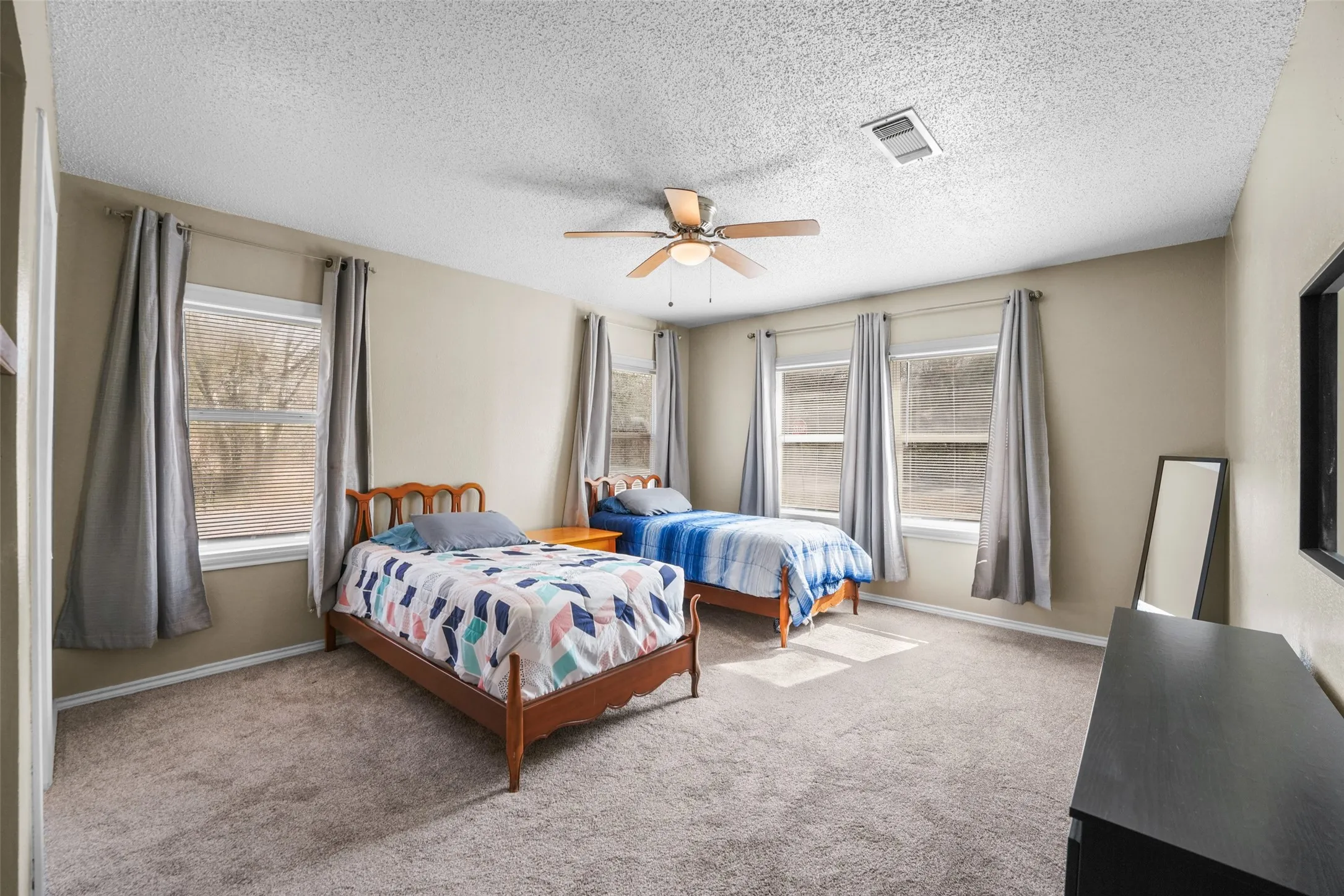 Carpeted bedroom featuring a textured ceiling and ceiling fan
