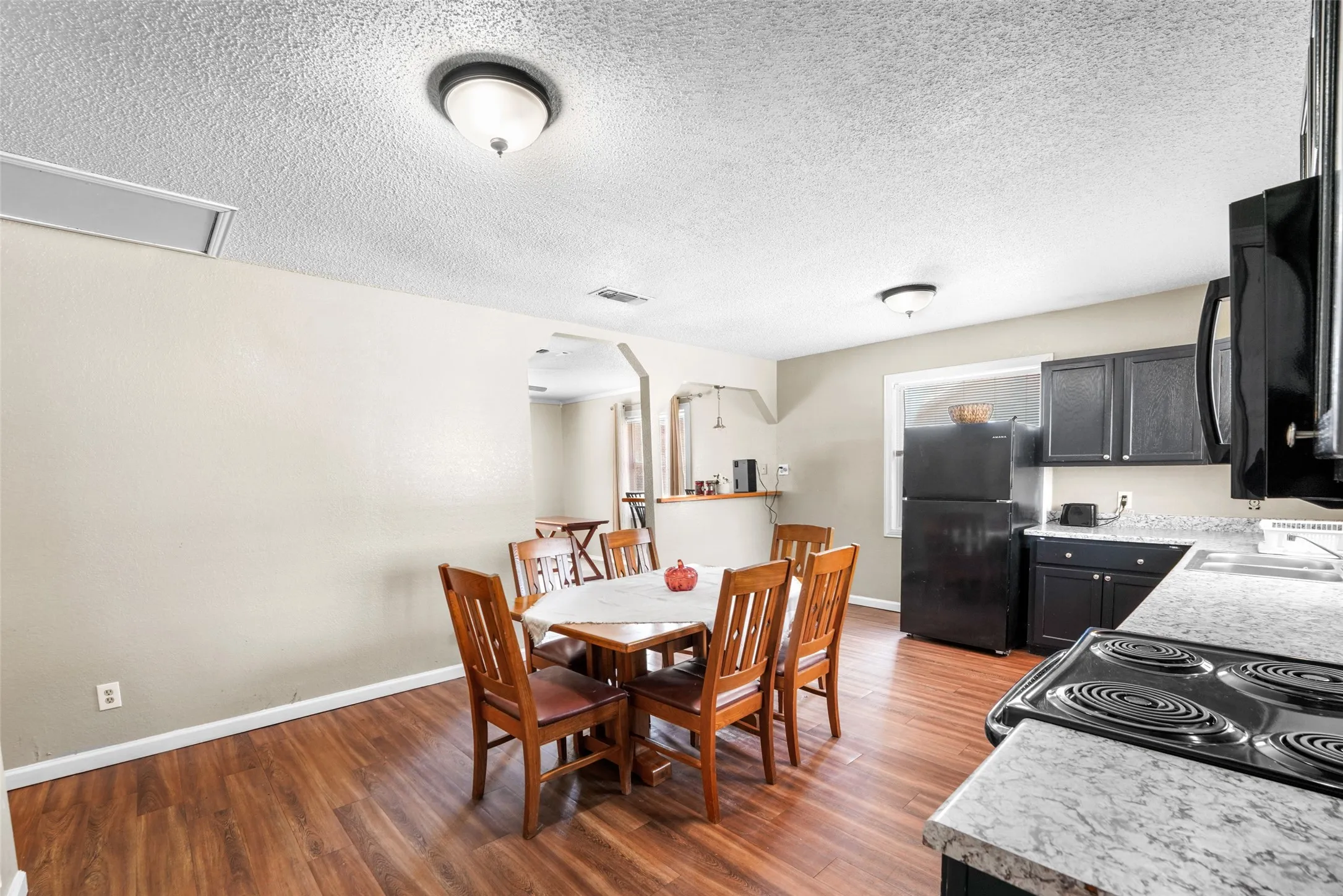 Dining area with dark wood-style flooring and a textured ceiling
