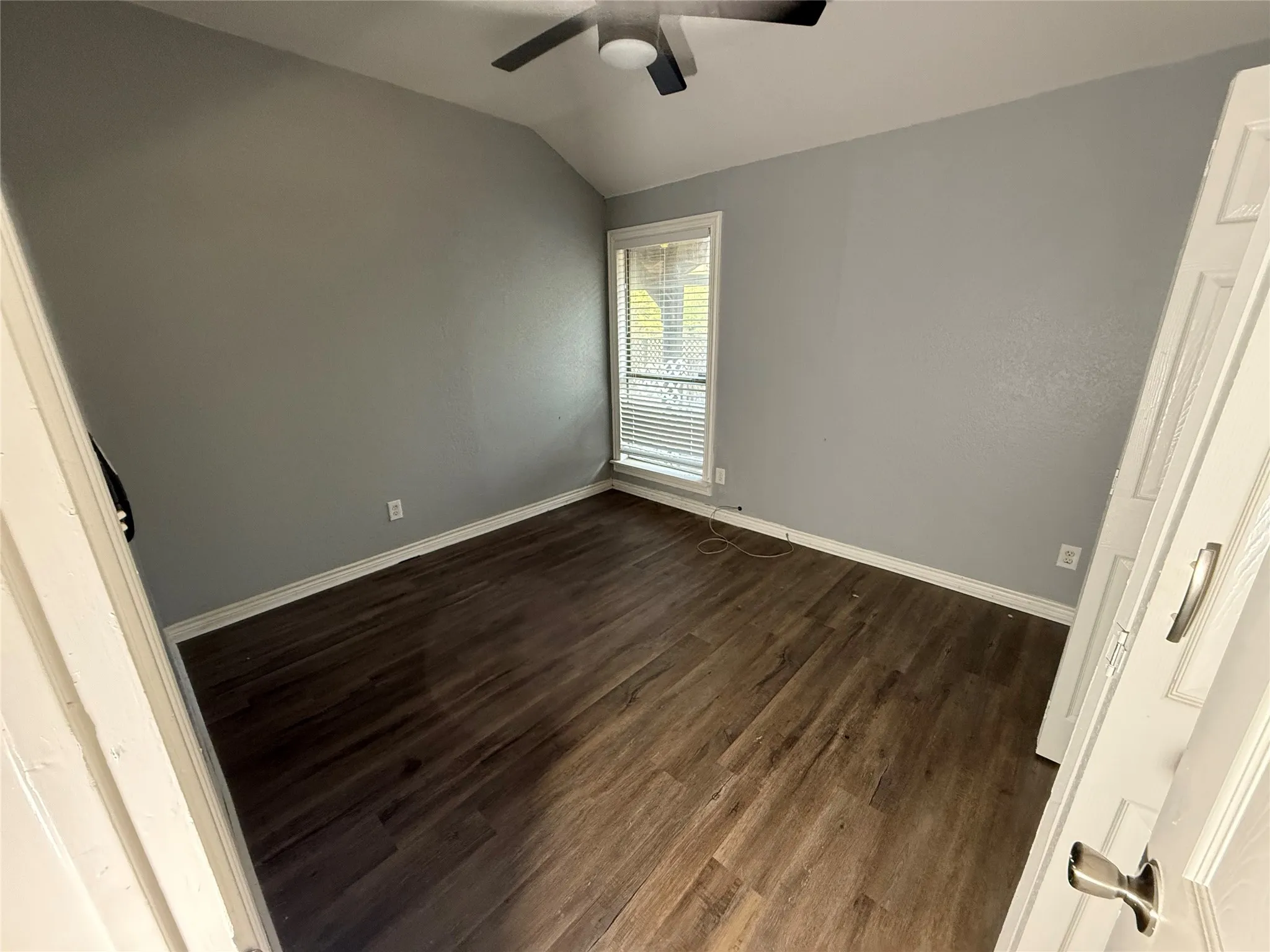 Unfurnished bedroom with dark wood finished floors, lofted ceiling, and ceiling fan