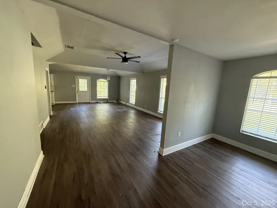 Unfurnished living room with ceiling fan, dark wood-type flooring, and vaulted ceiling