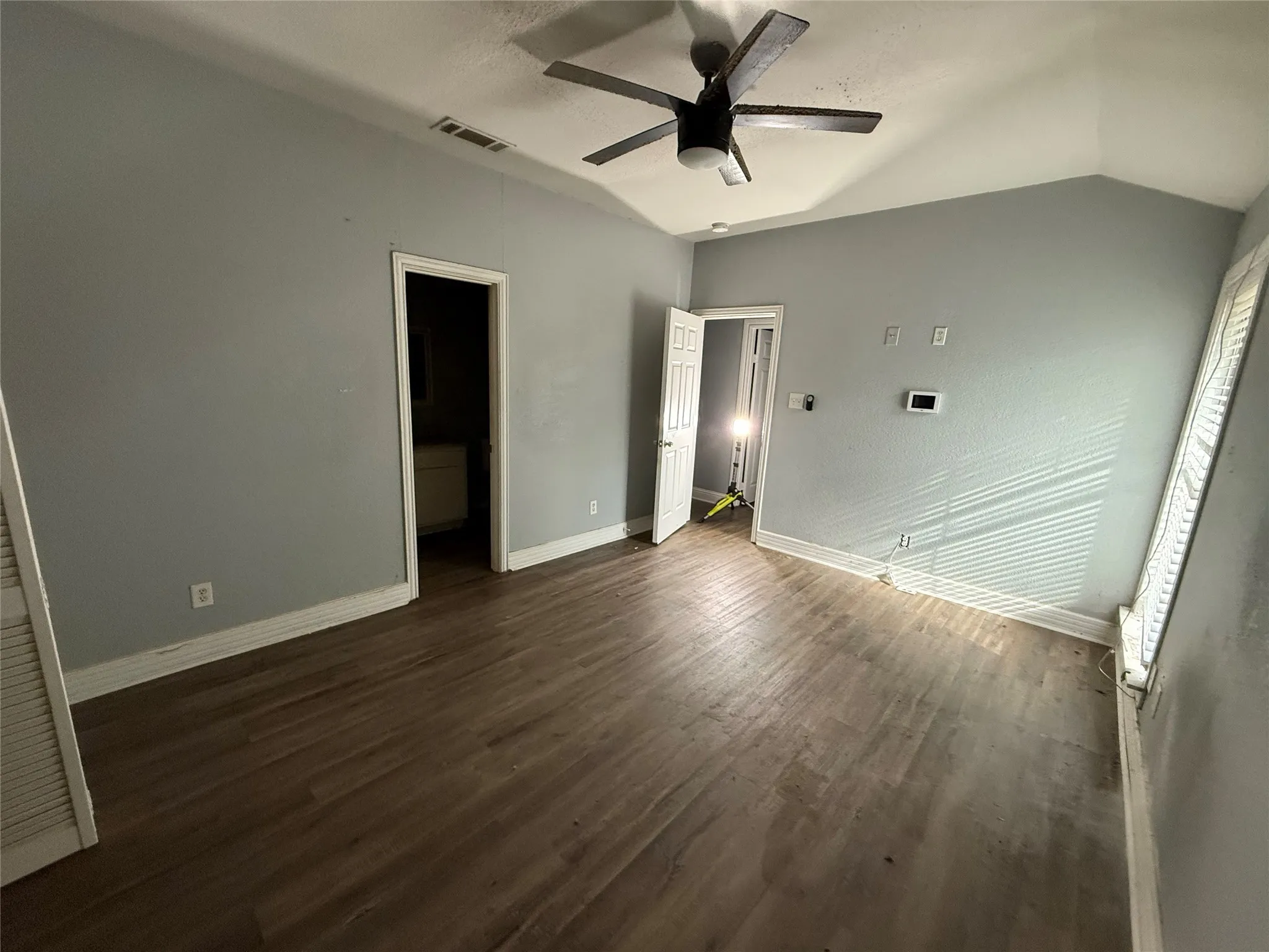 Unfurnished bedroom featuring vaulted ceiling, dark wood finished floors, and a ceiling fan
