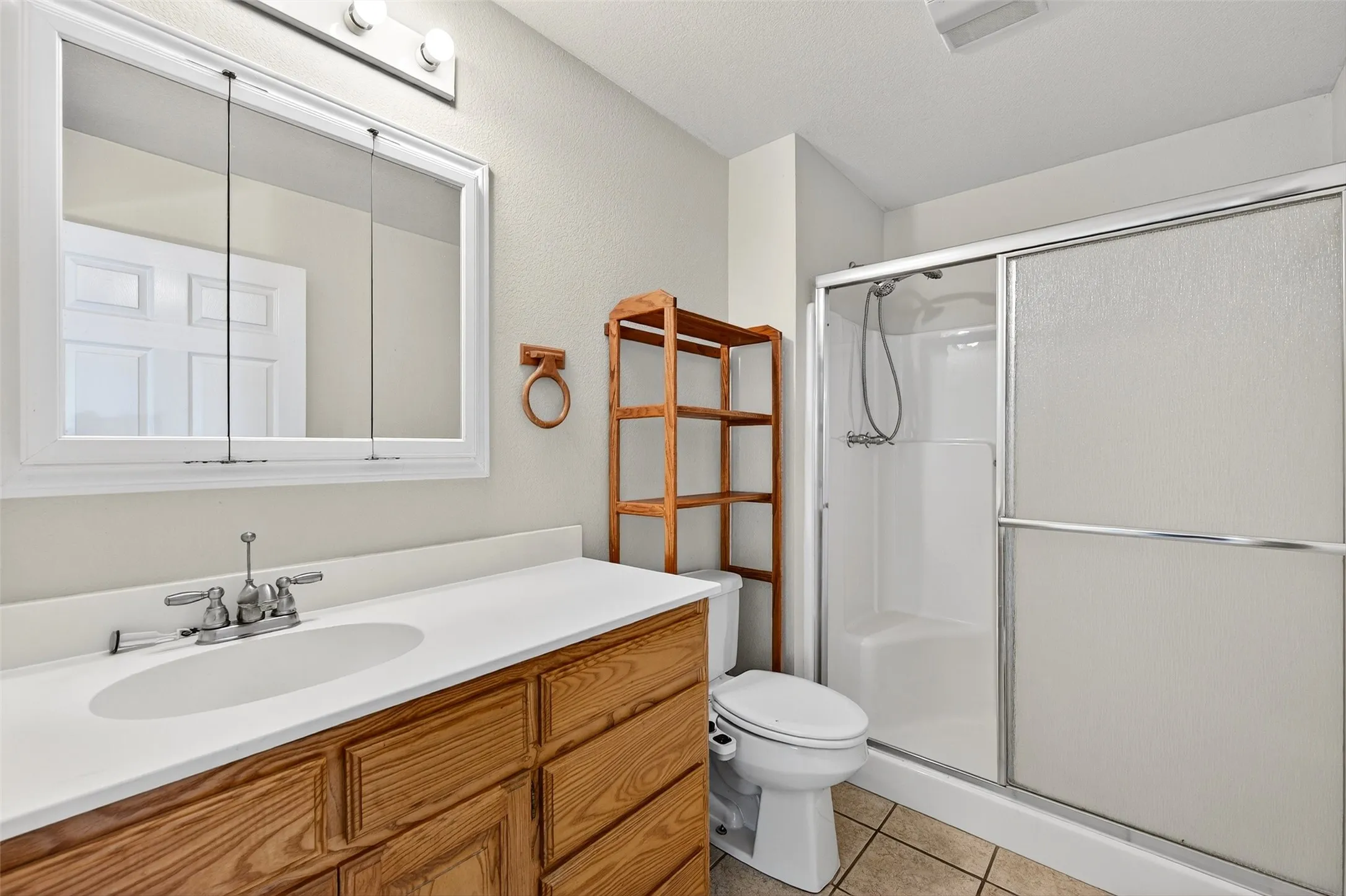 Bathroom featuring vanity, a shower stall, and light tile patterned floors