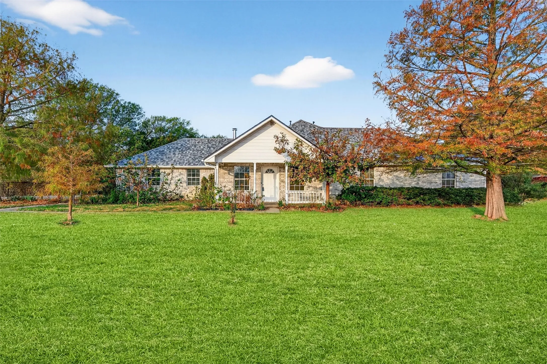 Single story home featuring a front yard, covered porch, and stone siding