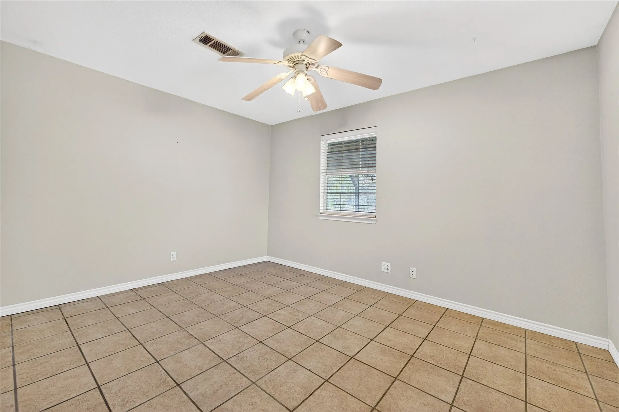 Empty room featuring ceiling fan and tile patterned flooring