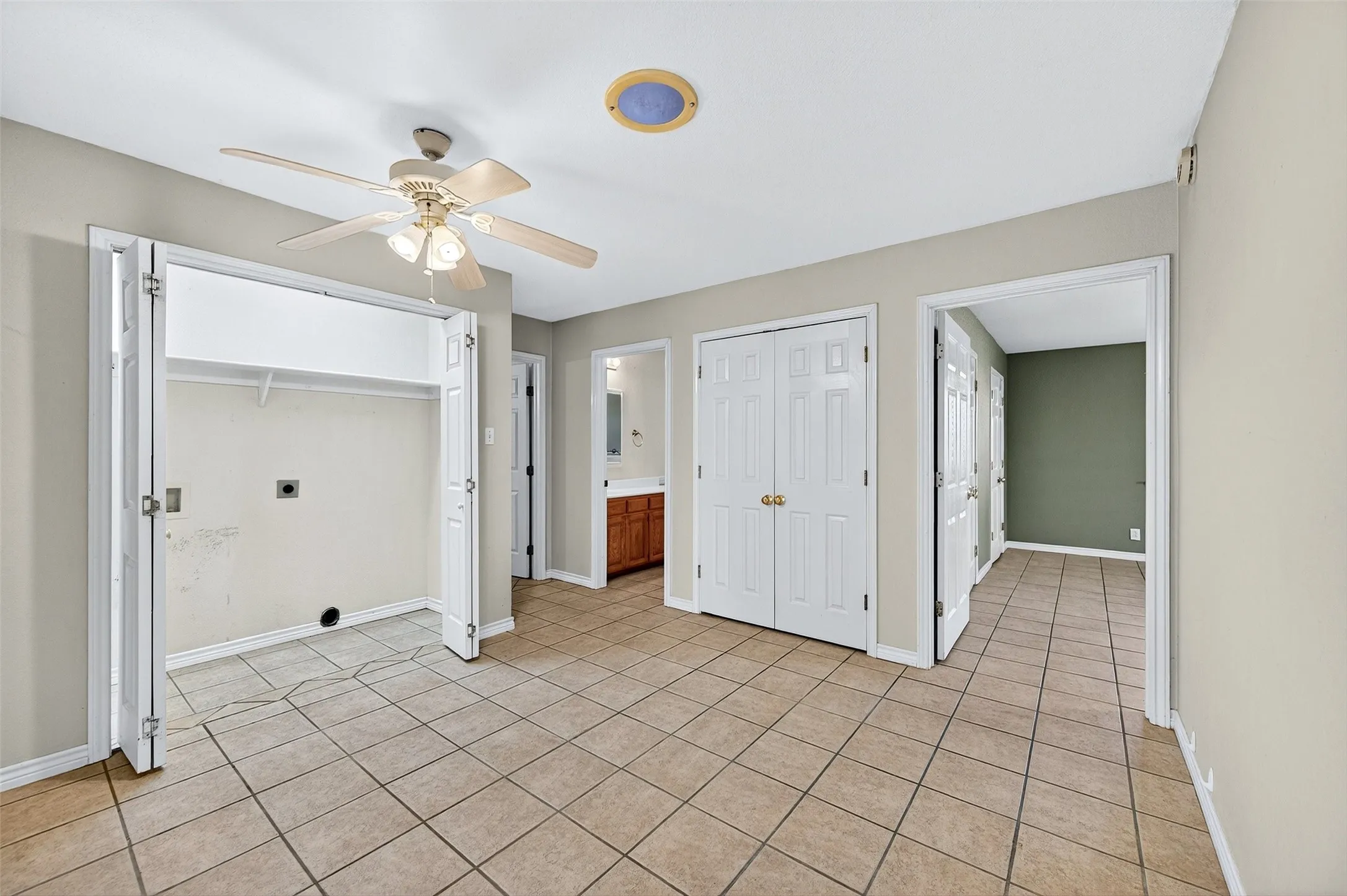 Unfurnished bedroom featuring two closets, ceiling fan, light tile patterned flooring, and ensuite bathroom