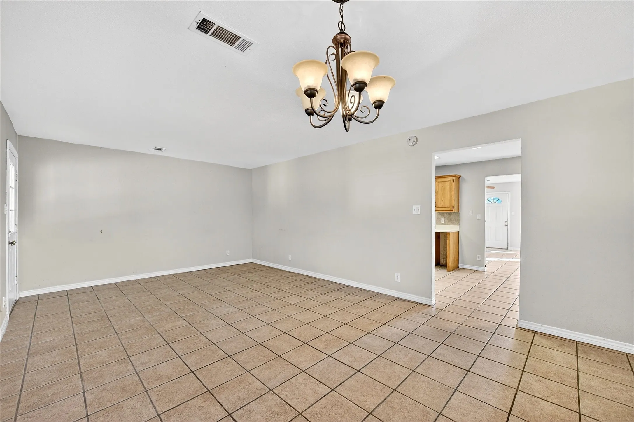 Spare room with a chandelier and light tile patterned flooring