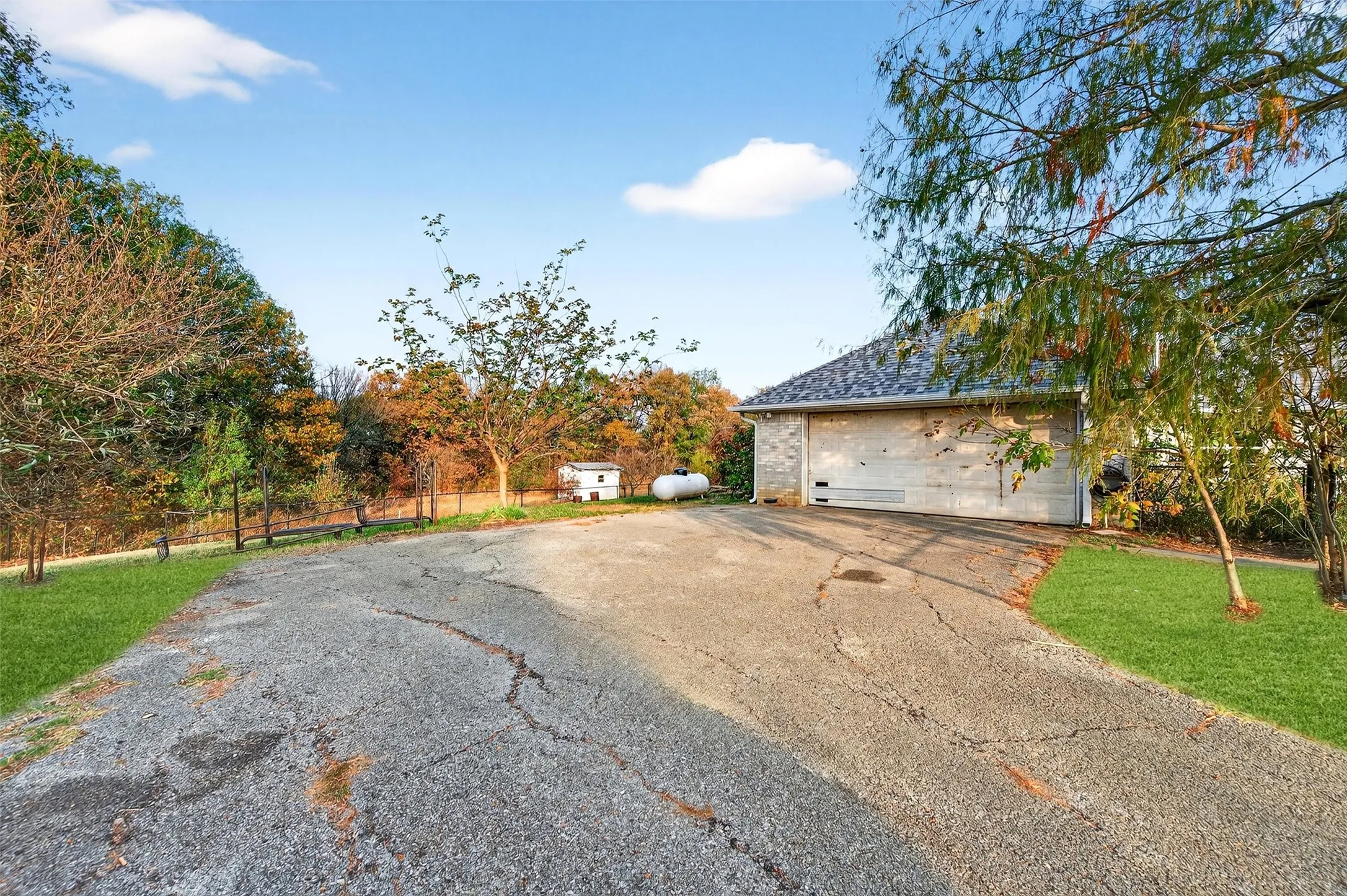 View of side of property with a garage, an outdoor structure, asphalt driveway, and brick siding