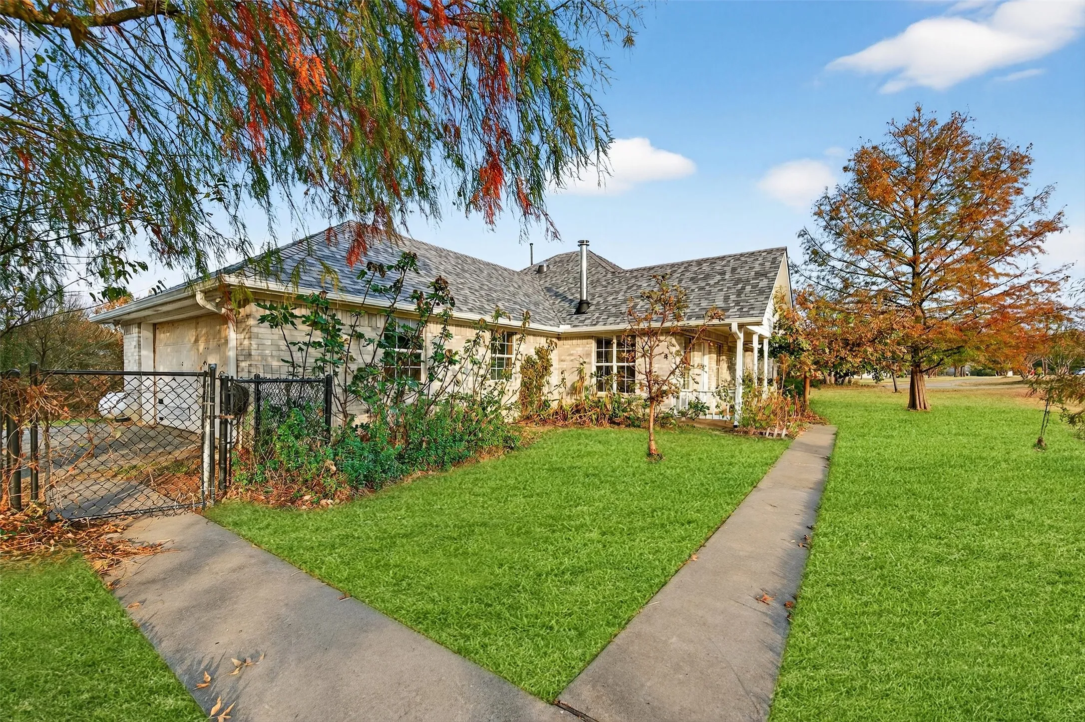 View of front of property with a gate, driveway, a shingled roof, and a garage