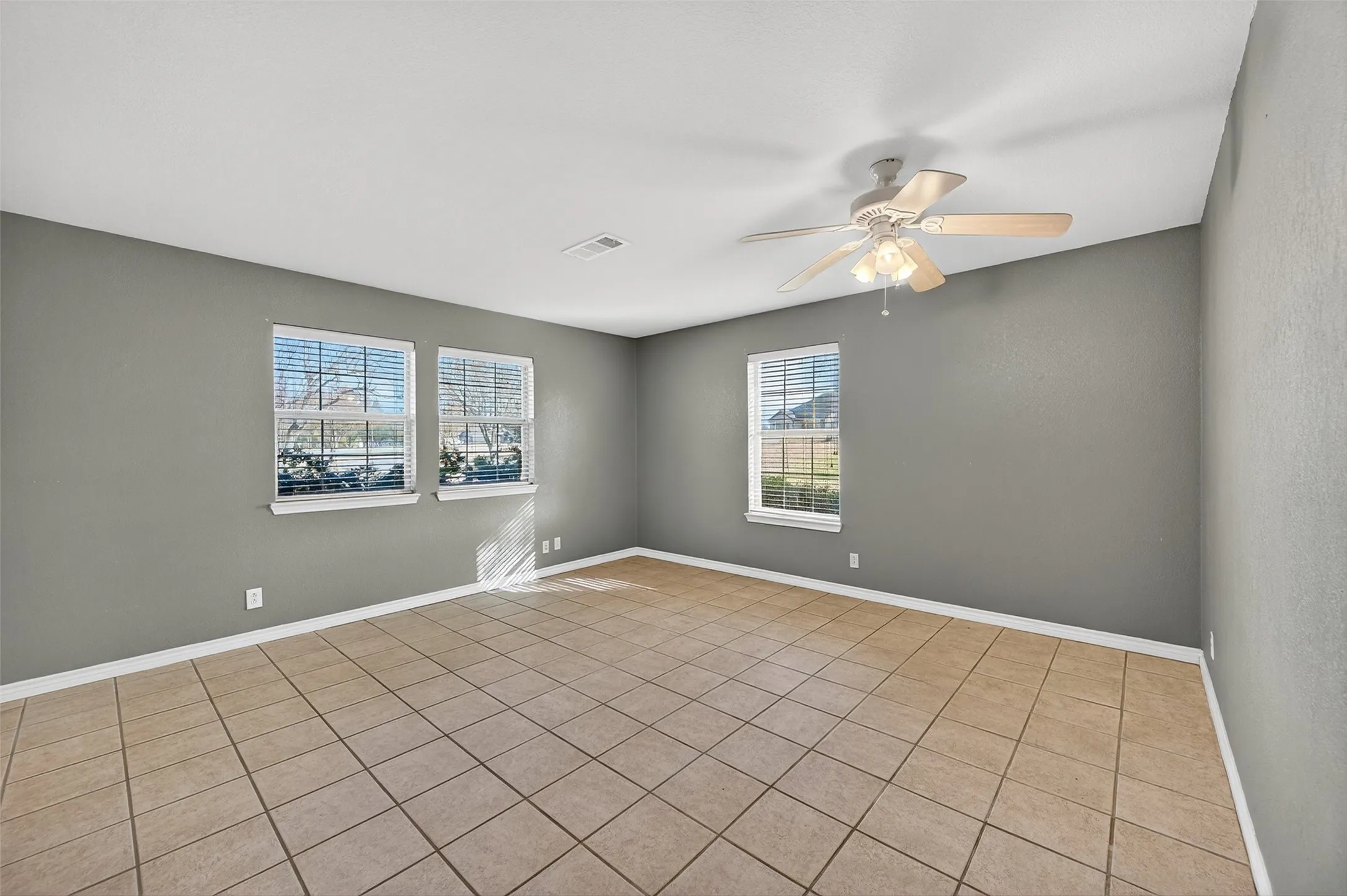 Empty room featuring light tile patterned floors and ceiling fan