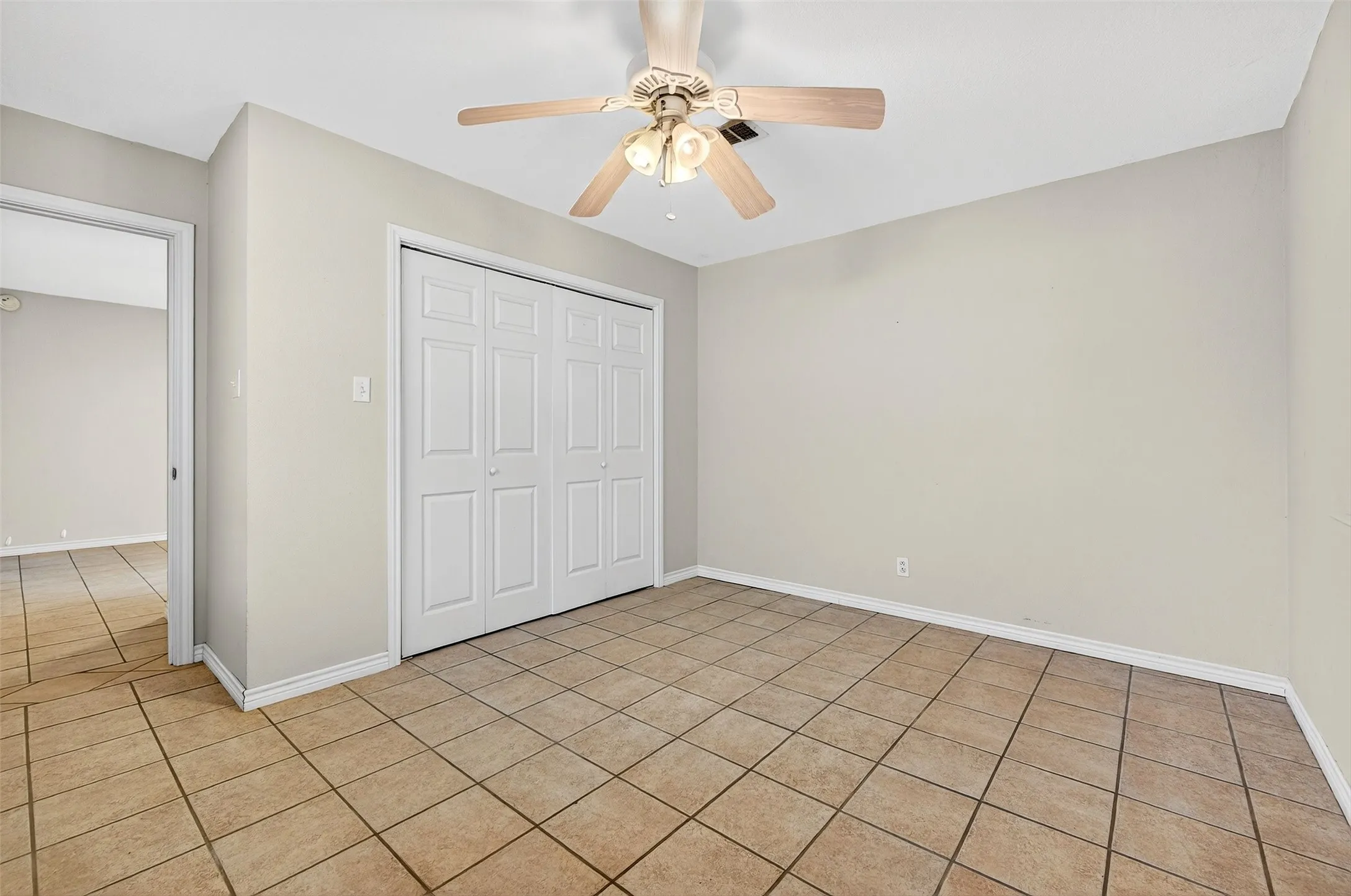 Unfurnished bedroom with a closet, ceiling fan, and light tile patterned flooring