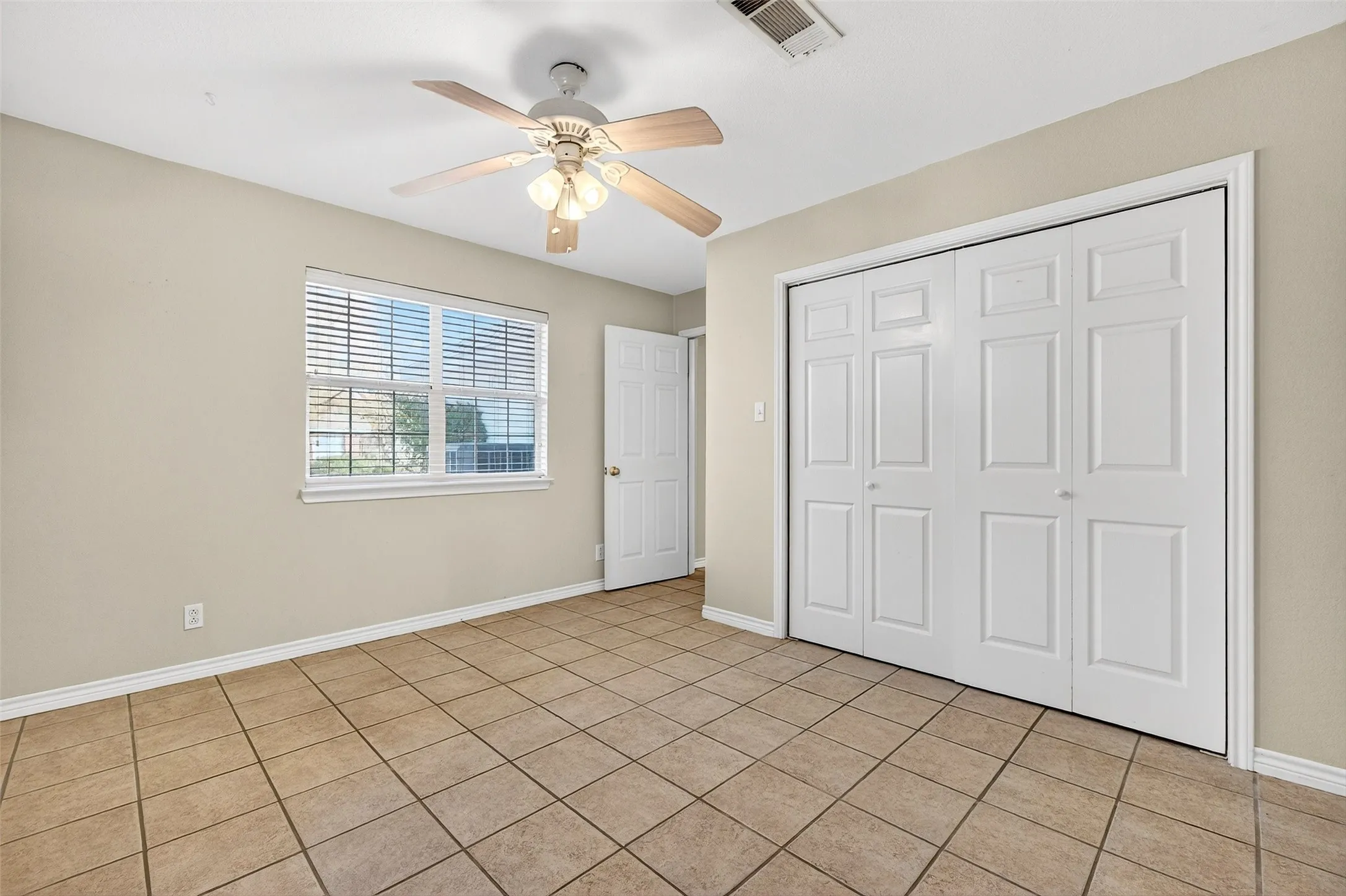 Unfurnished bedroom featuring ceiling fan, a closet, and light tile patterned floors