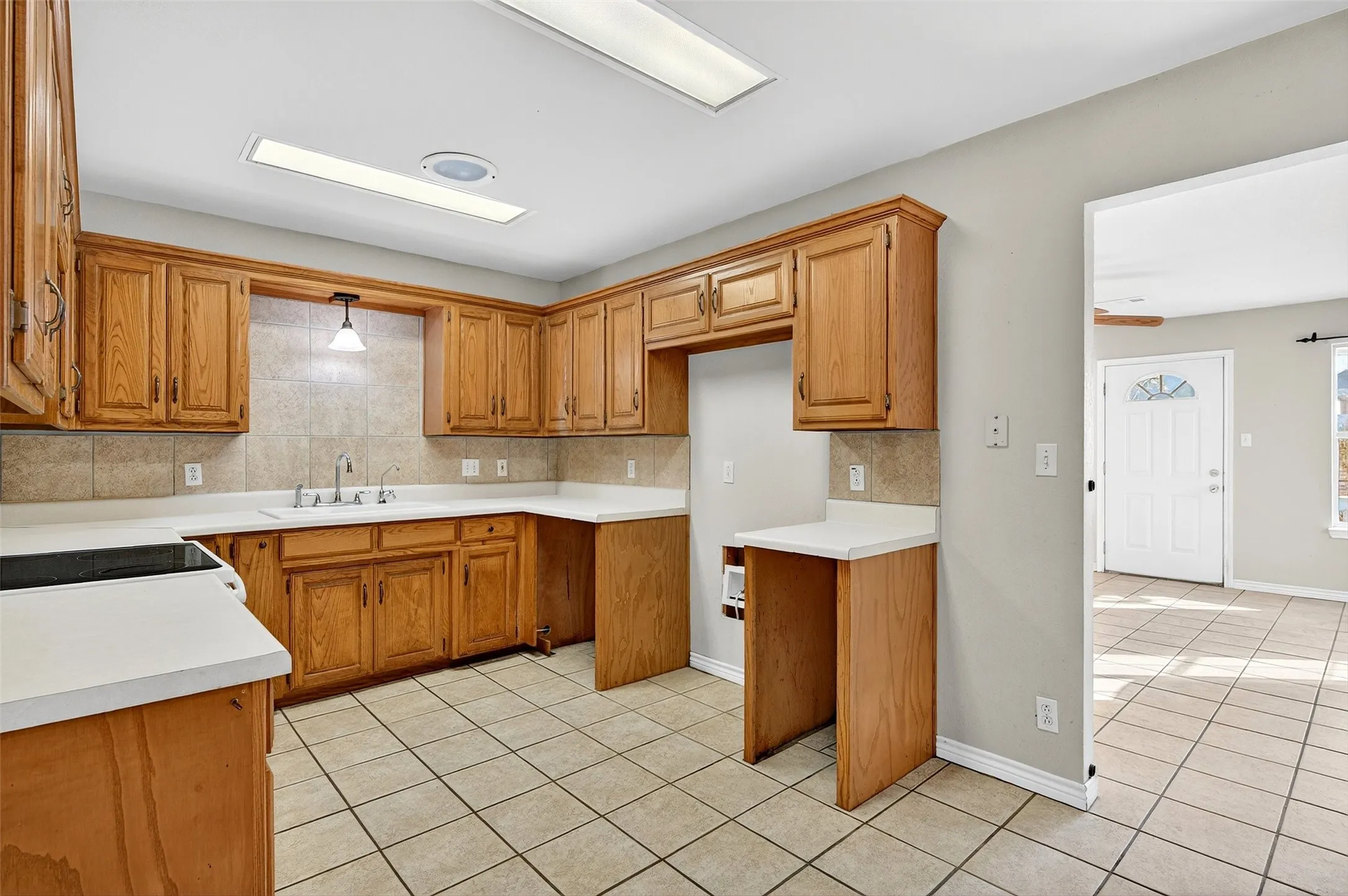 Kitchen with light tile patterned floors, brown cabinets, and light countertops