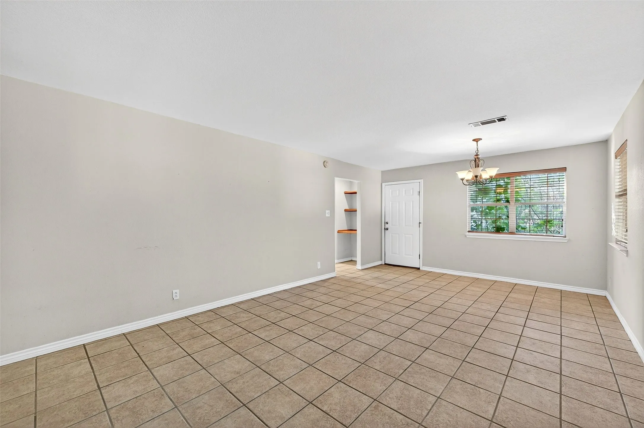 Spare room featuring a chandelier and tile patterned flooring