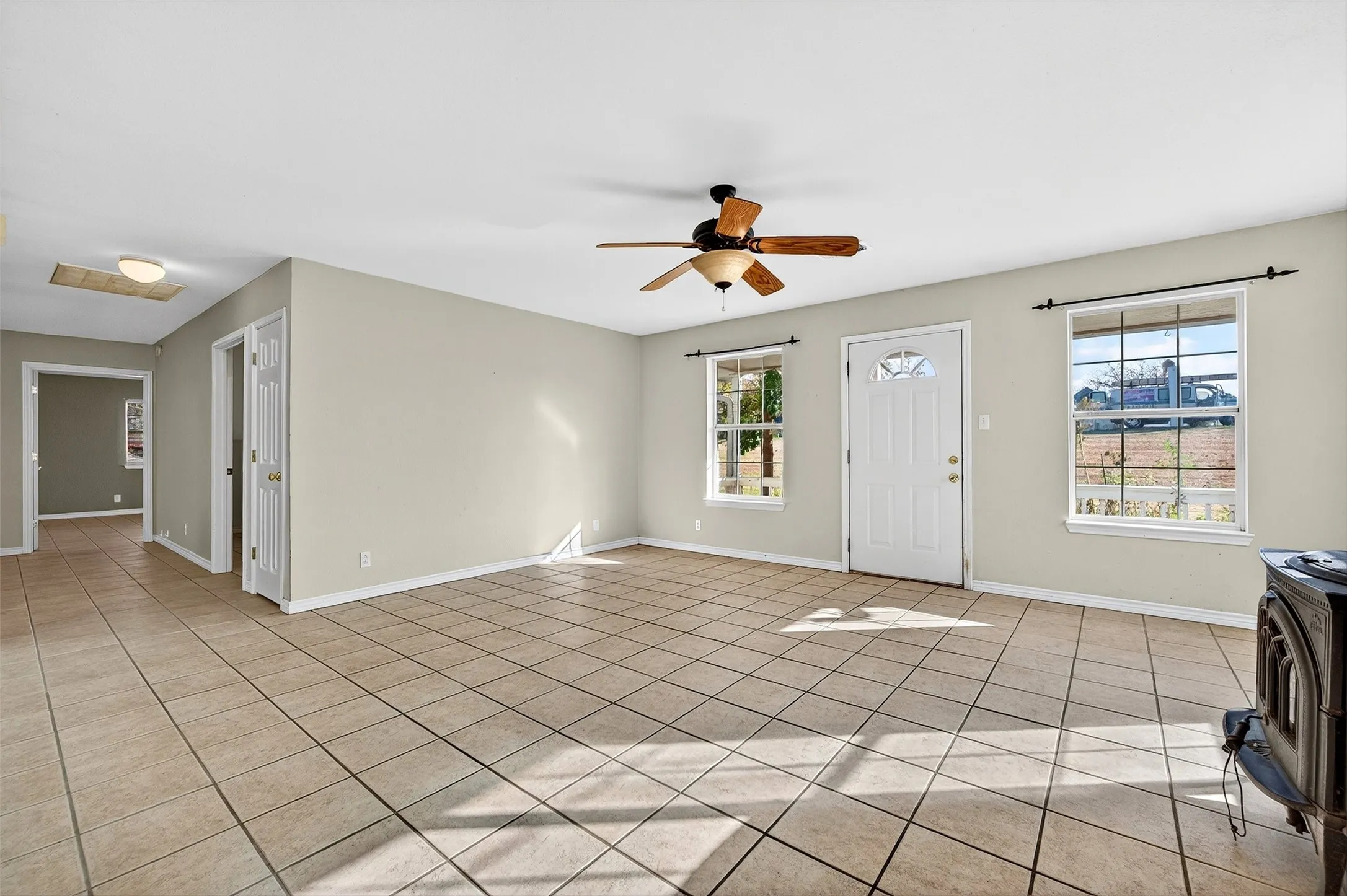 Foyer entrance featuring a wood stove, ceiling fan, and light tile patterned floors