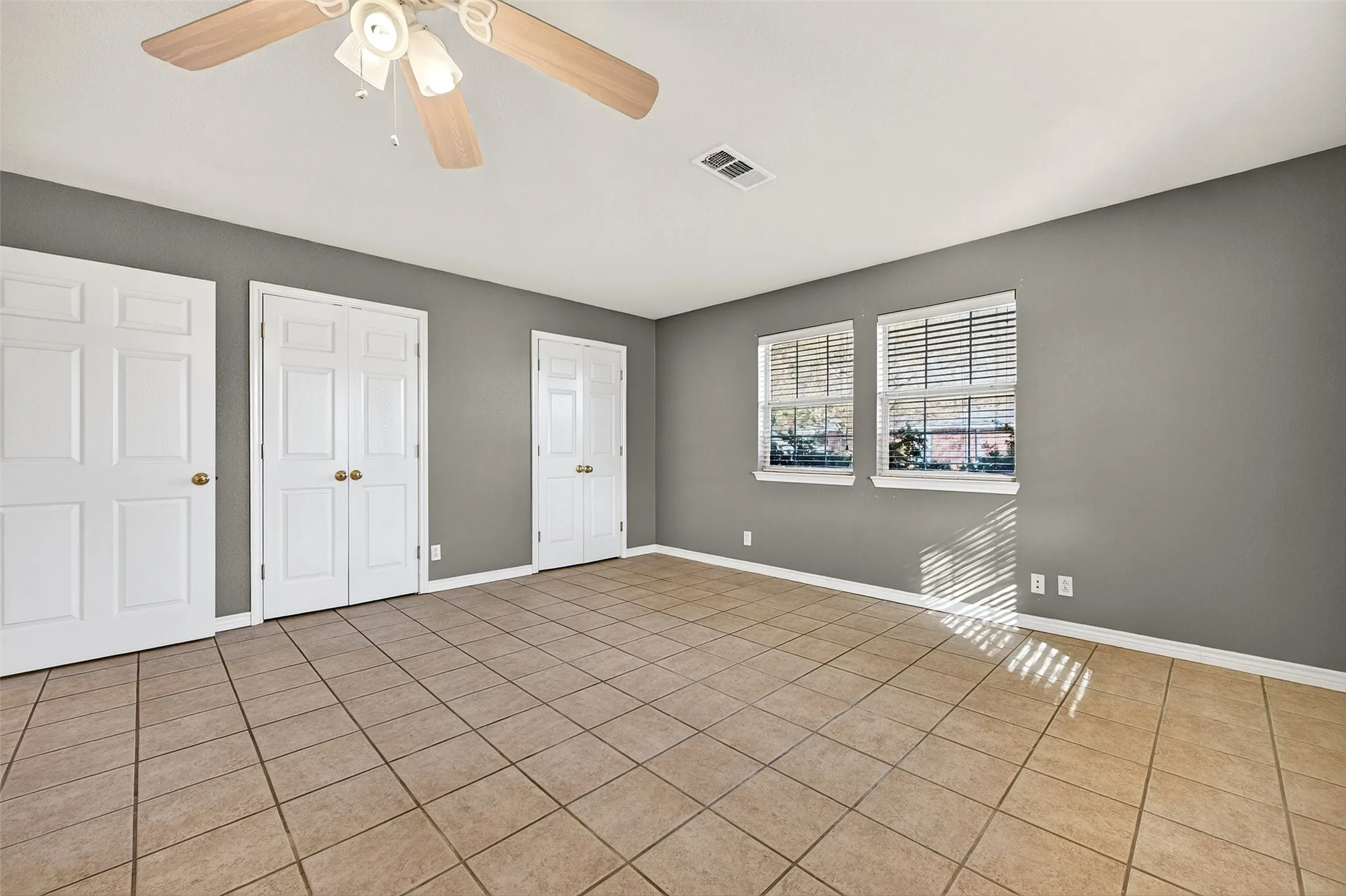 Unfurnished bedroom featuring two closets, a ceiling fan, and tile patterned floors