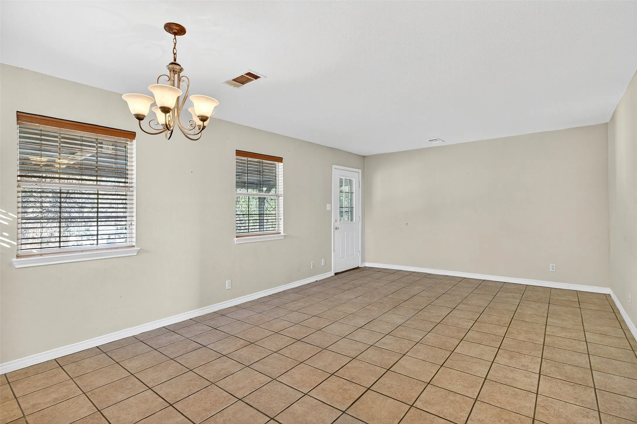 Empty room featuring a chandelier and tile patterned flooring