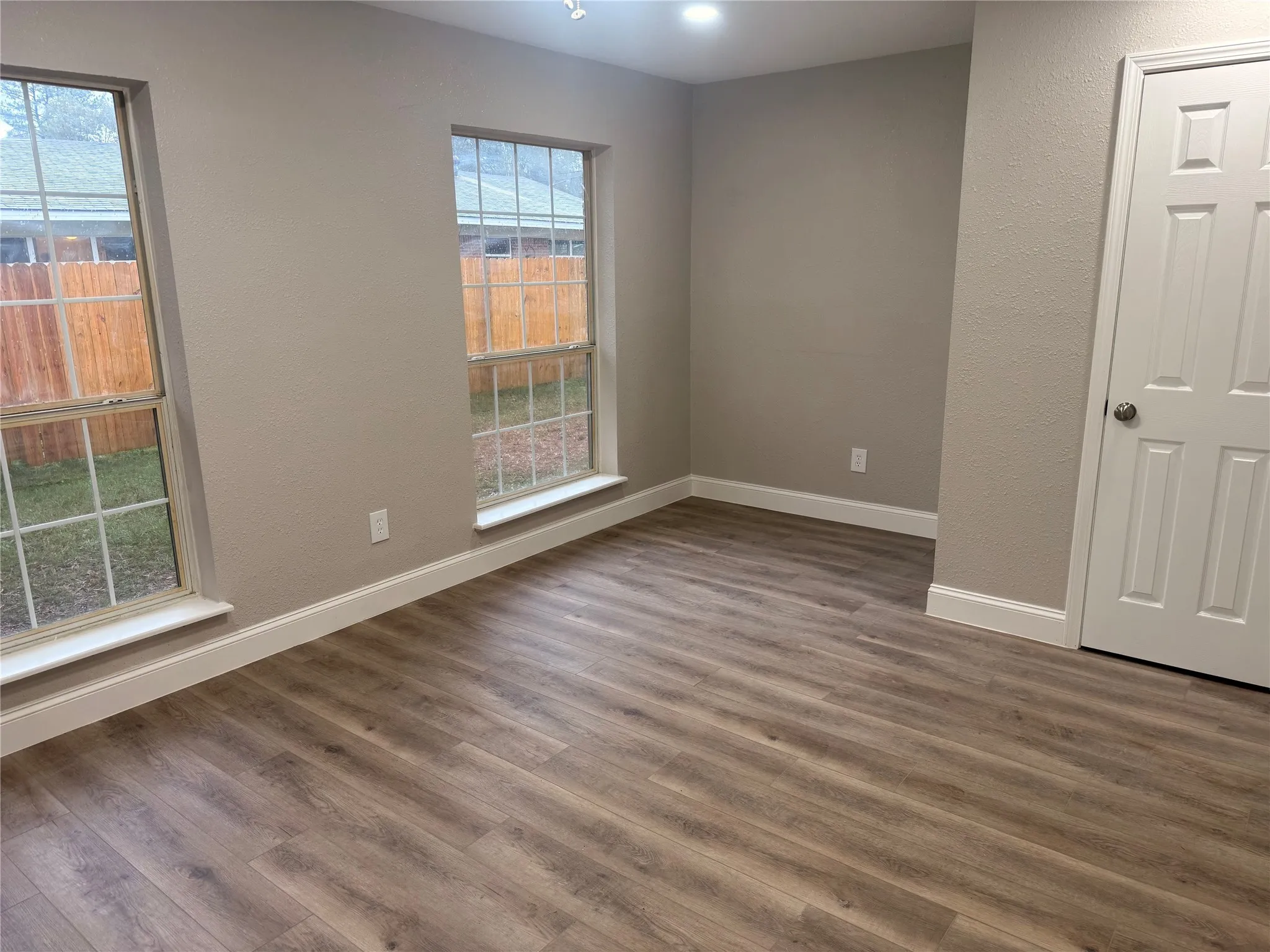 Unfurnished room featuring dark wood-style flooring and a textured wall