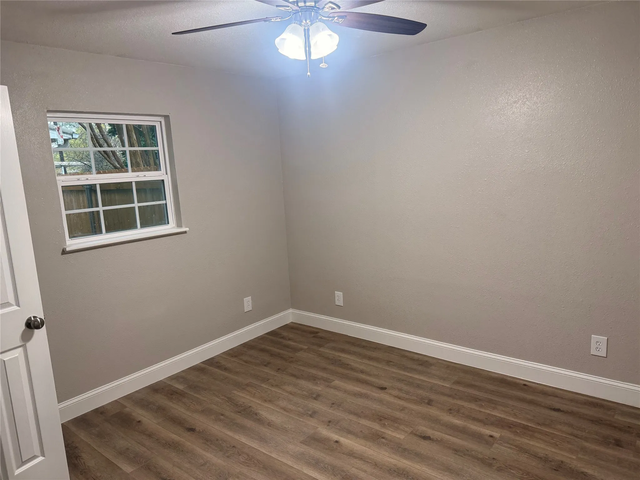 Unfurnished room featuring dark wood-style flooring and a ceiling fan