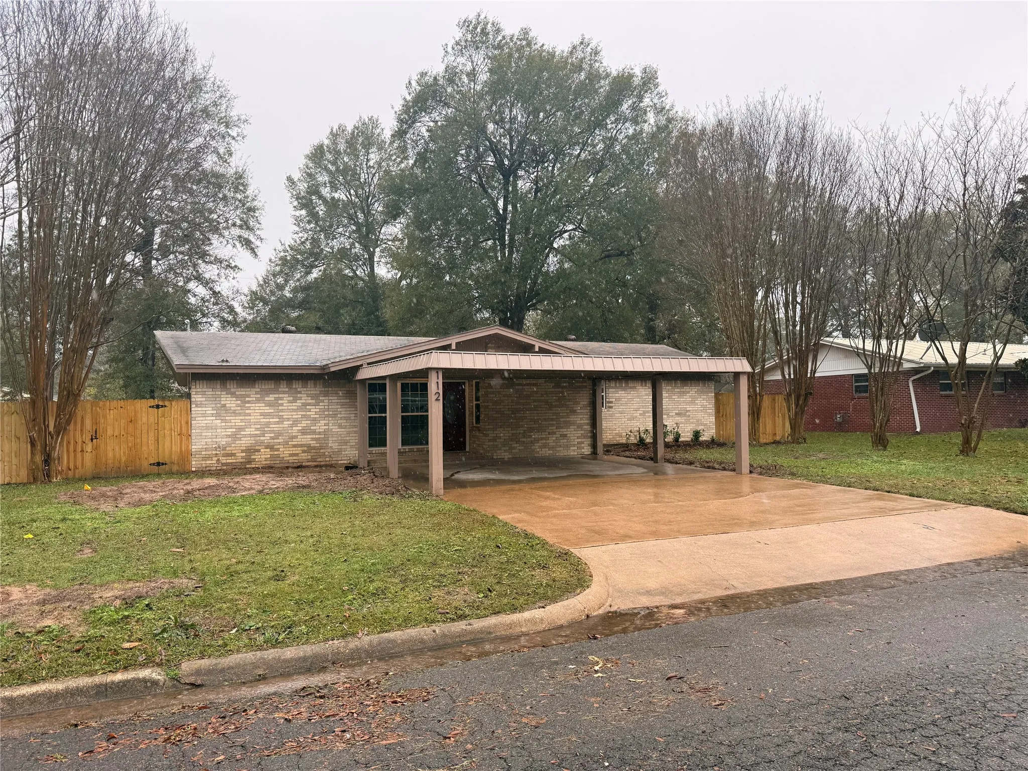 Mid-century home featuring brick siding, concrete driveway, and a carport