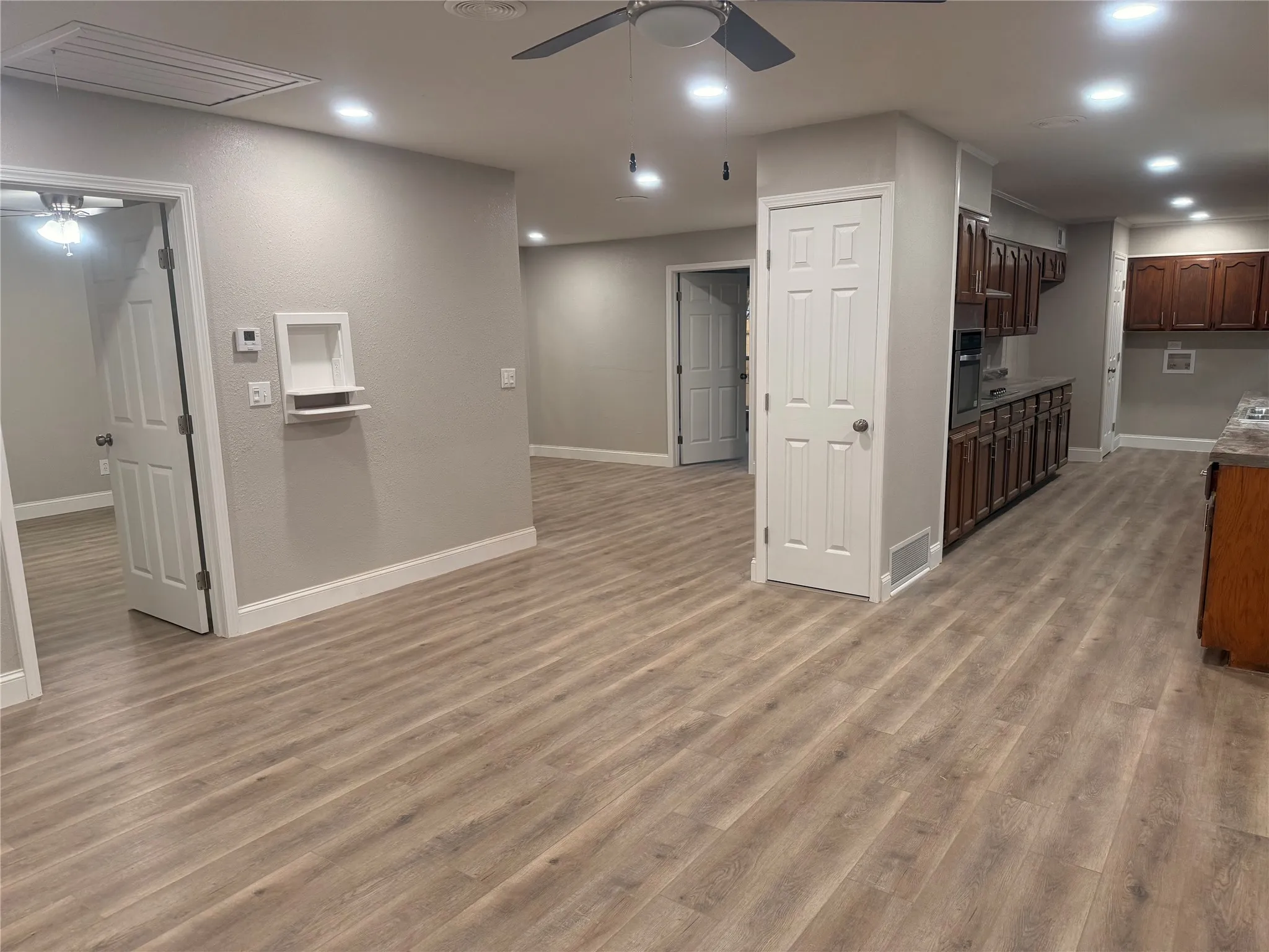 Kitchen with a ceiling fan, recessed lighting, dark brown cabinets, light wood-style flooring, and oven