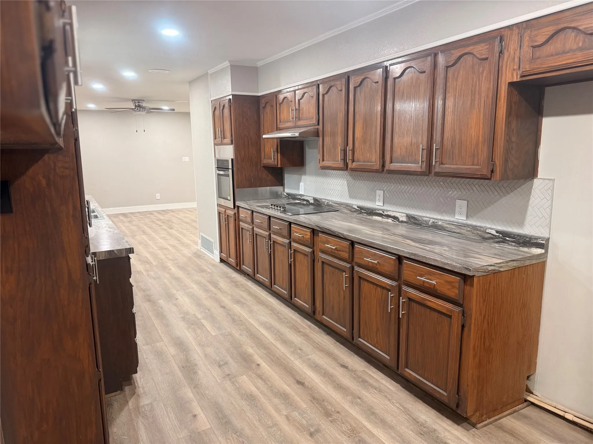 Kitchen featuring dark countertops, light wood-style floors, ceiling fan, recessed lighting, and oven