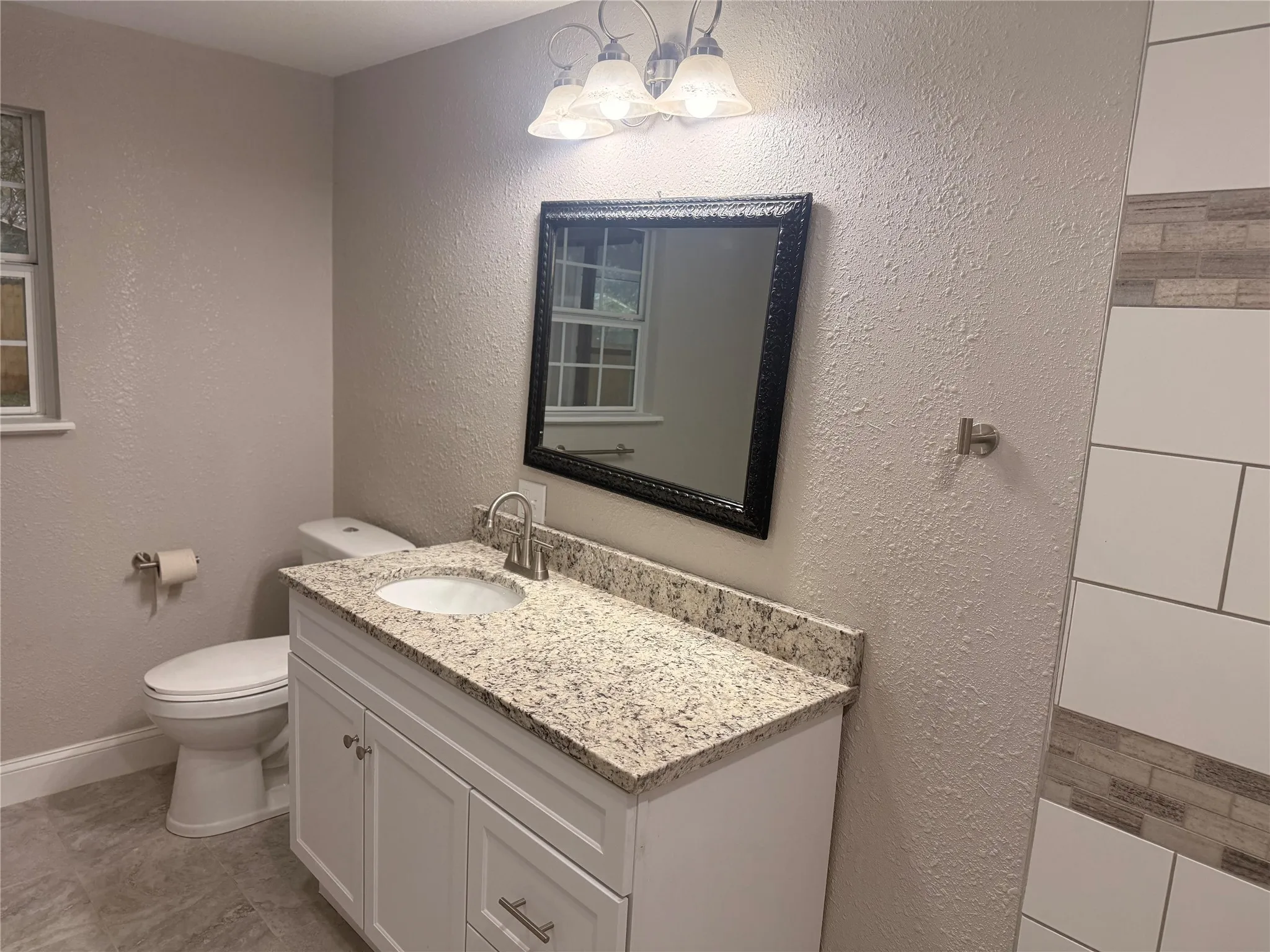 Half bathroom with a textured wall and vanity