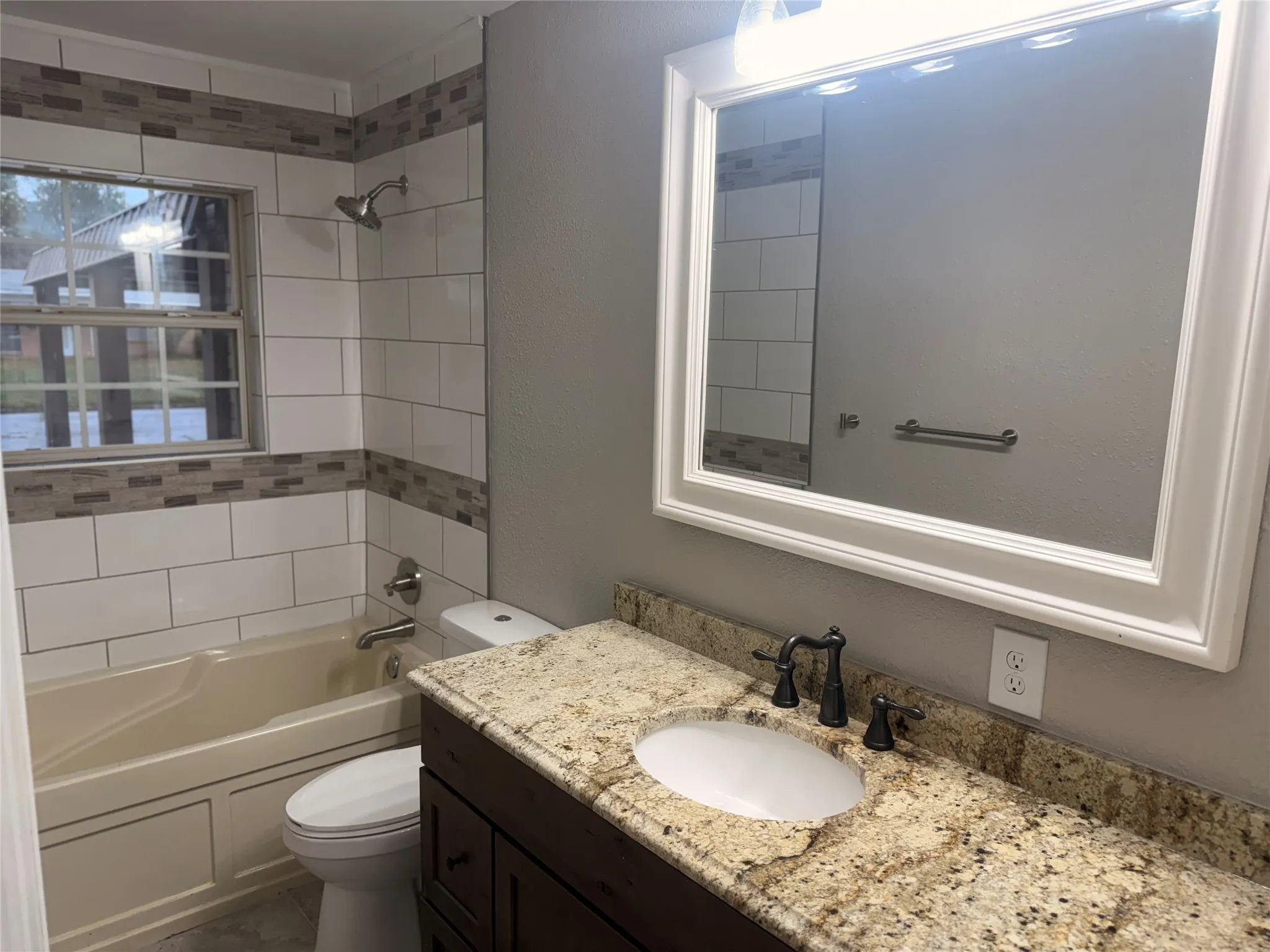 Full bathroom featuring shower / bathtub combination, vanity, and a textured wall
