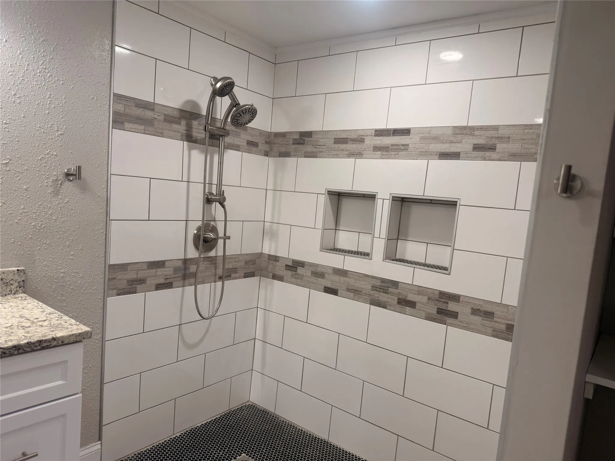 Bathroom featuring vanity, tiled shower, and a textured wall