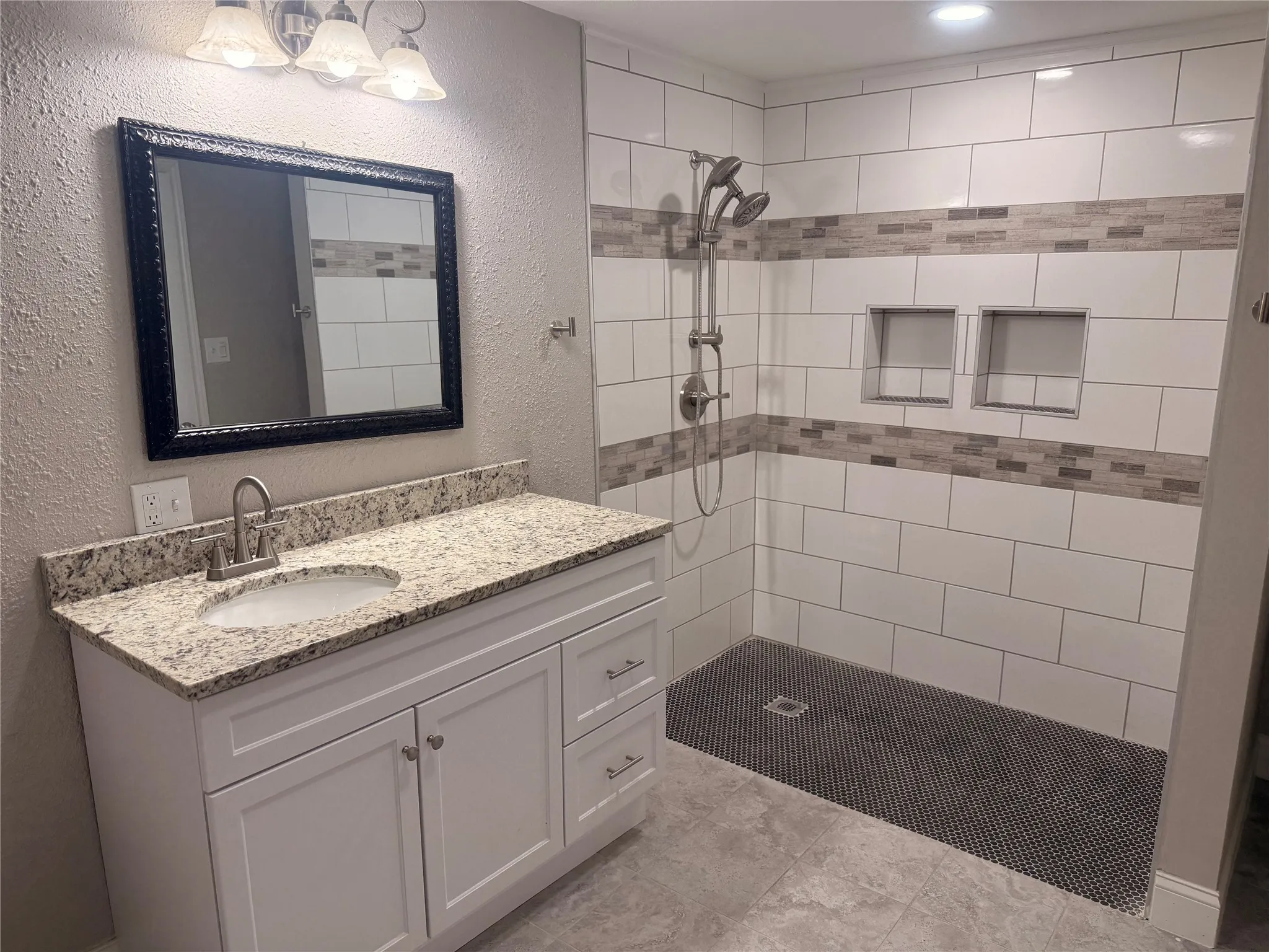 Full bath featuring a textured wall, vanity, and a stall shower